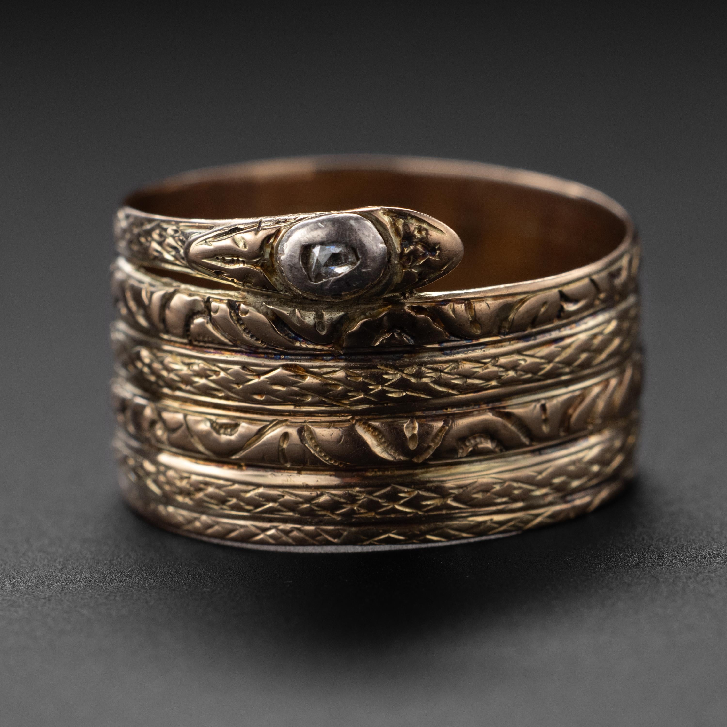 Spectacular and rare: this 19th-century snake ring was created by hand-pulled gold wire which was pounded flat, coiled, fused and engraved with rich detailing. A small diamond set inside a chunky silver bezel forms the crown of the snake. This thin