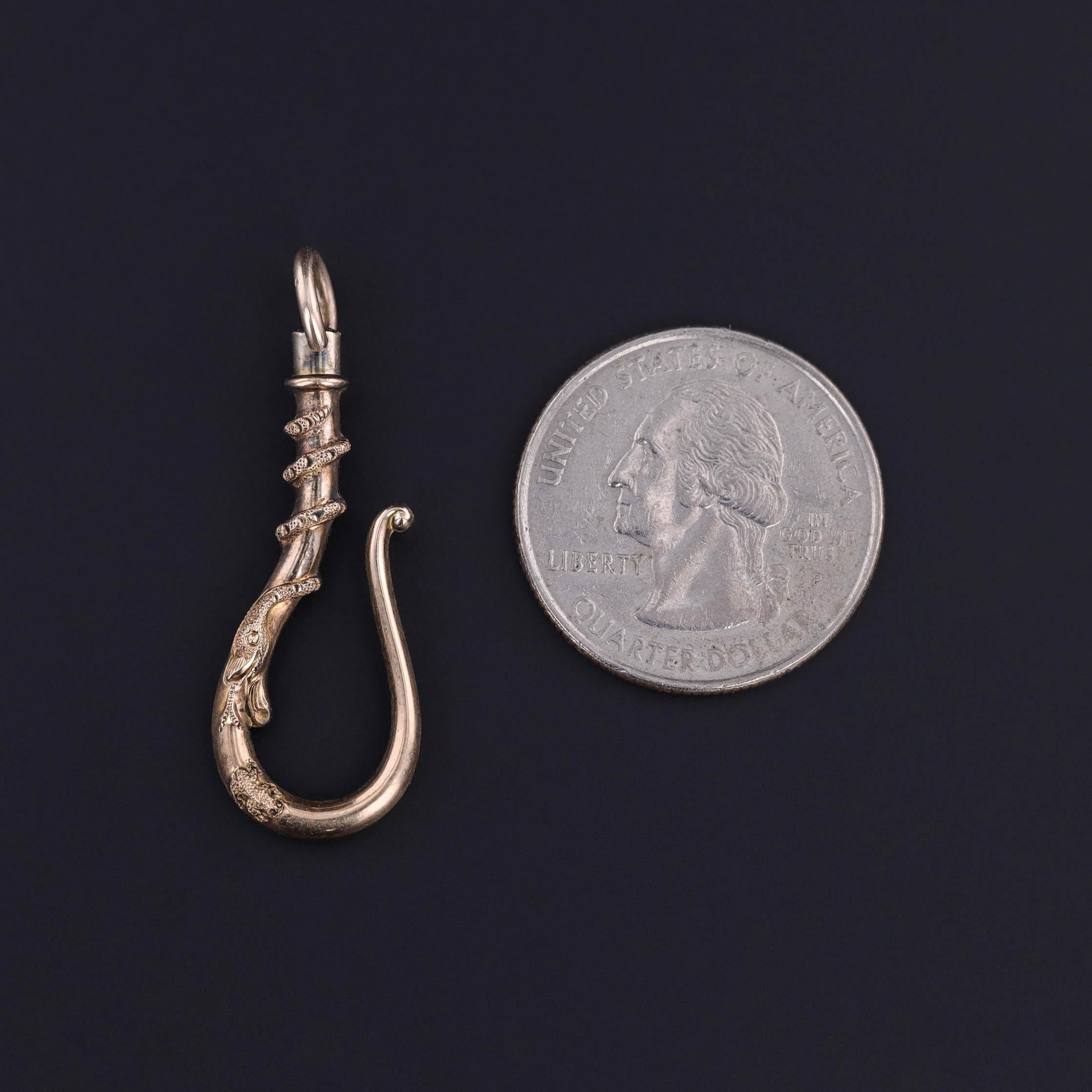 An antique watch hook or charm holder of 14k gold with a snake of gold entwined around it.

The piece measures 1.5 inches from the top of the bail to bottom by 0.5 inches wide and weighs 3.04 grams. It is in great condition.

The metal content of
