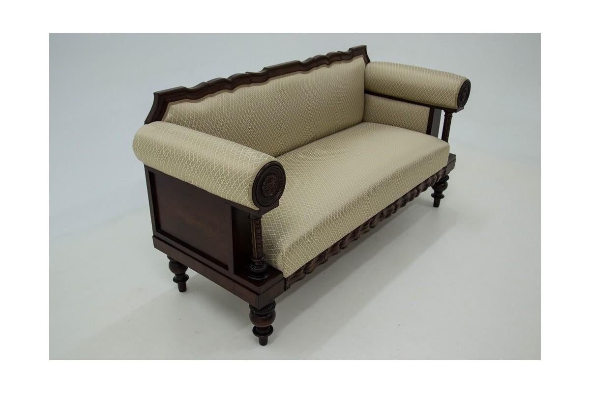 An antique, mahogany sofa was made at the end of the 19th century. The frame of the sofa has a wavy outline, armrests in the form of rollers decorated on the front with carved medallions. Seat, back and backrests of the side sofas upholstered with