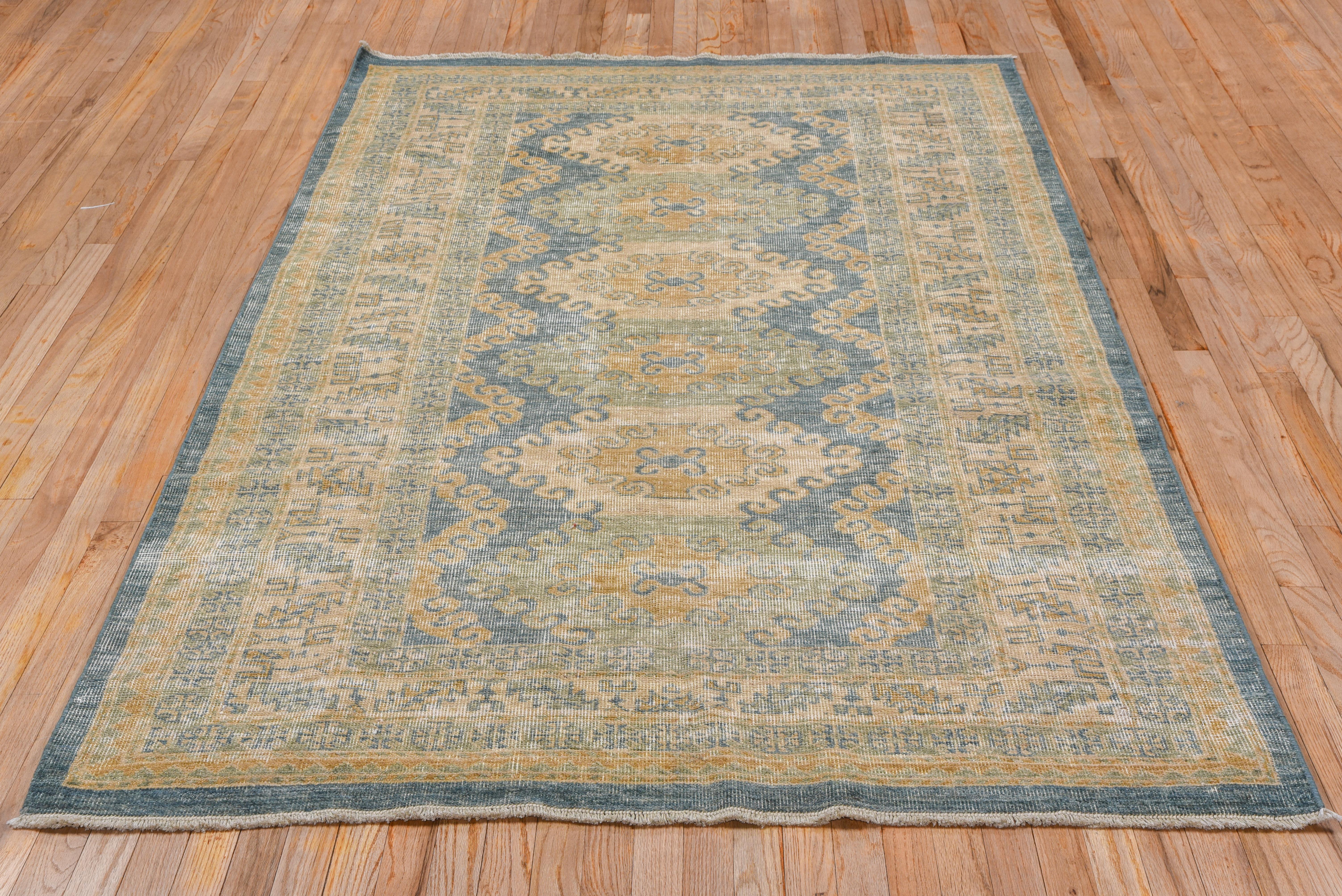 This Oushak rug has six flattened, hooked hexagons decorate the soft blue field of this rustic Anatolian scatter with cream, salmon and dull goldenrod accents, within a Classic calyx and slated, serrated leaf border.
 