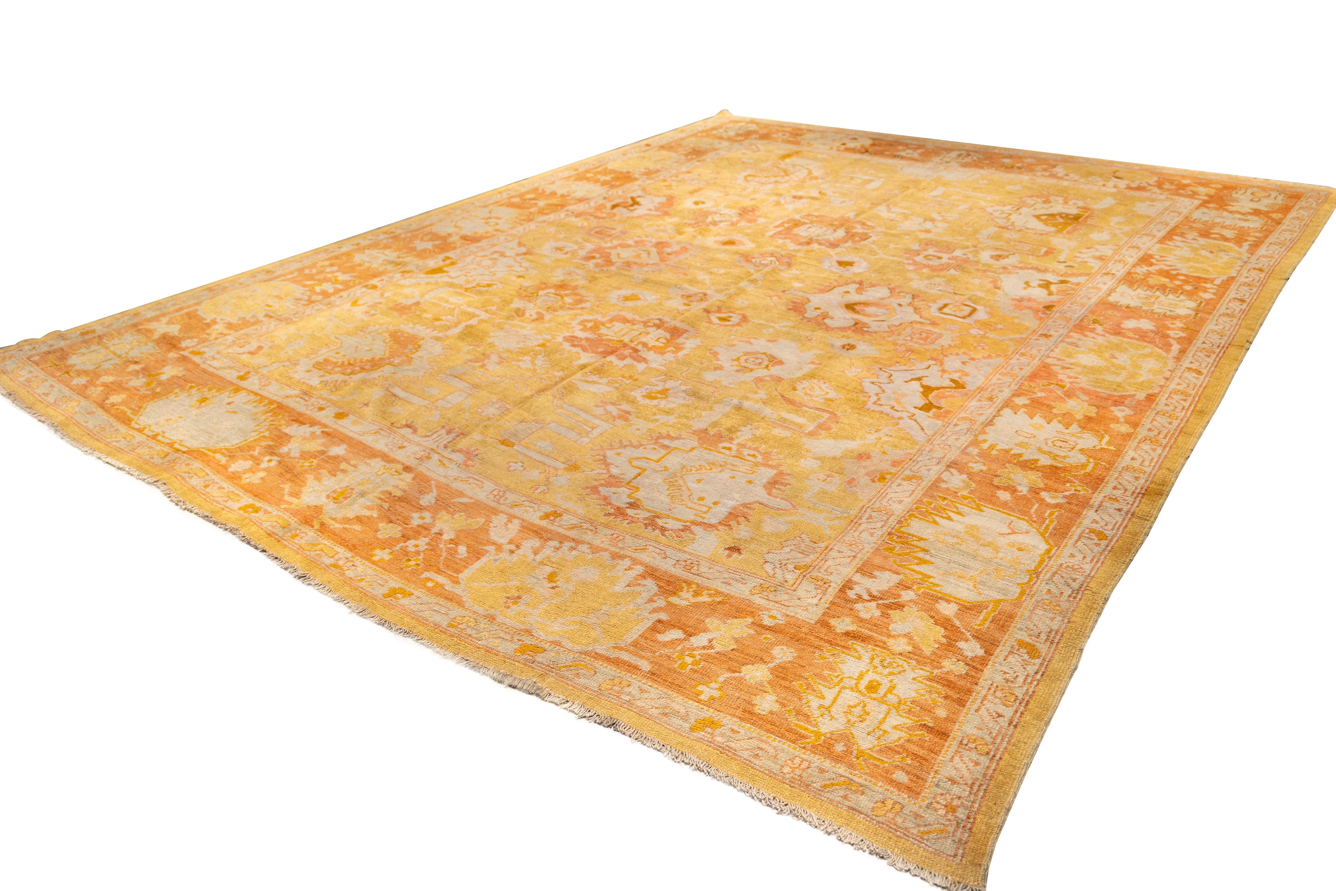 antique Oushak rug early to 20th century with warm color palette dominated by soft golds, saffron yellows, and muted oranges. 

The central field is a golden yellow, with faded and distressed areas giving it a soft, aged patina. With a stylized