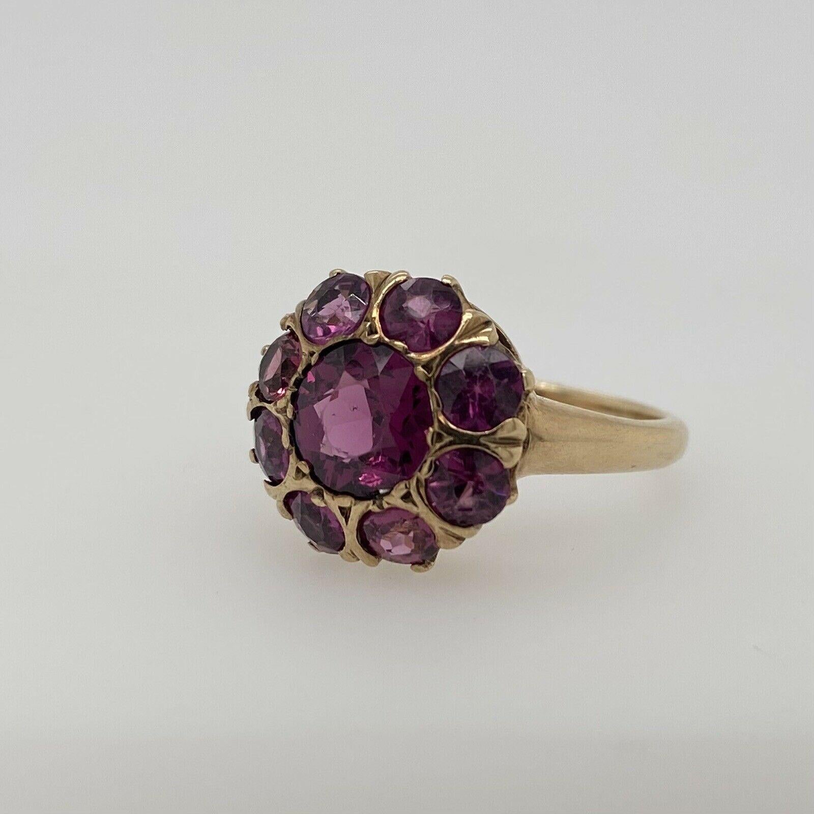 This antique 10K yellow gold ring features a genuine purple sapphire in the center measuring approximately 7.25mm. It is surrounded by 8 smaller genuine purple sapphires that measure approximately 3.70mm each. This ring is a size 6.25 and weighs 4.0