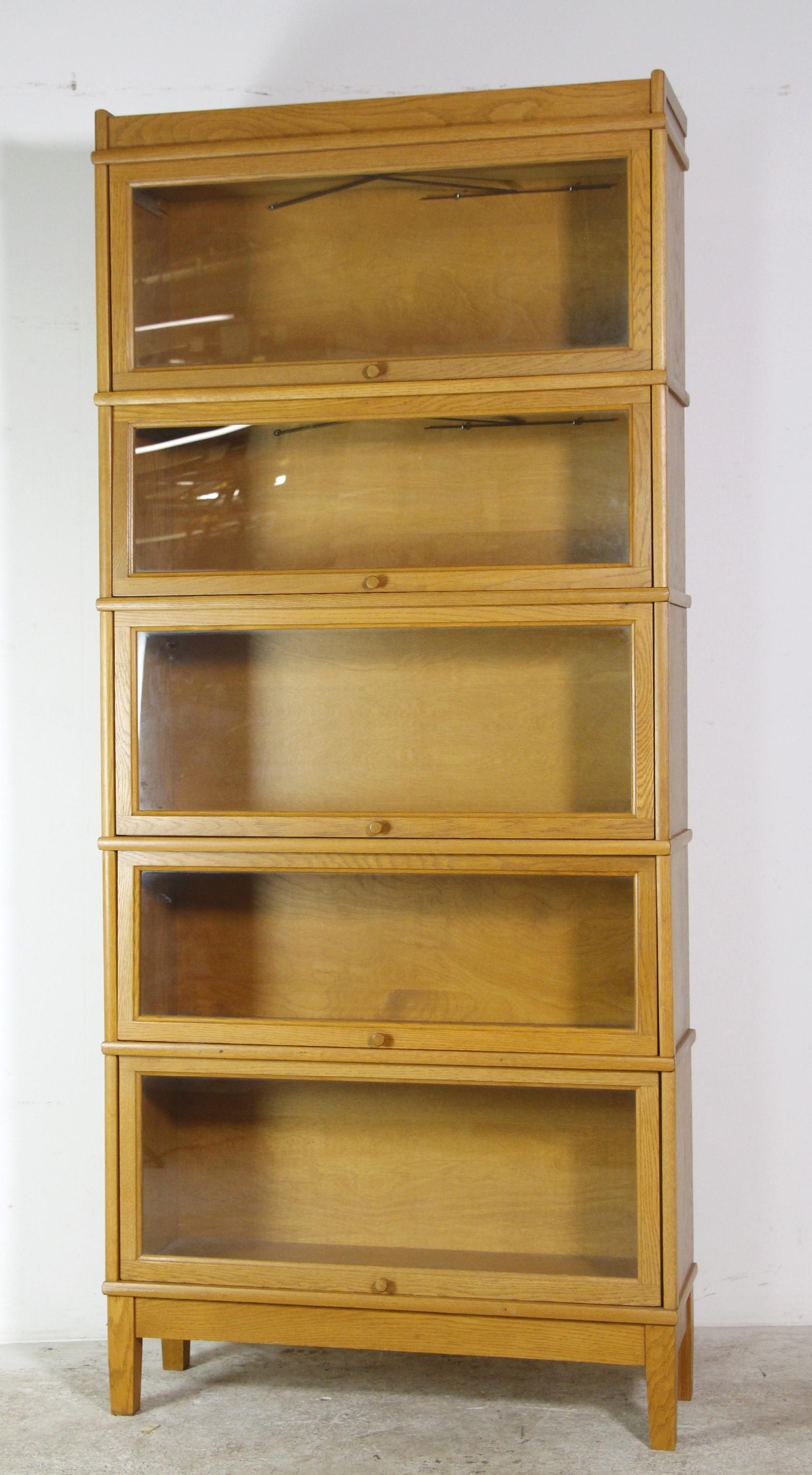 Antique solid oak barrister bookcase, five sections with glass pull-down doors. The glass front doors have wooden knobs and are in good working condition. The original glass is intact. Please note, this item is located in one of our NYC locations.
