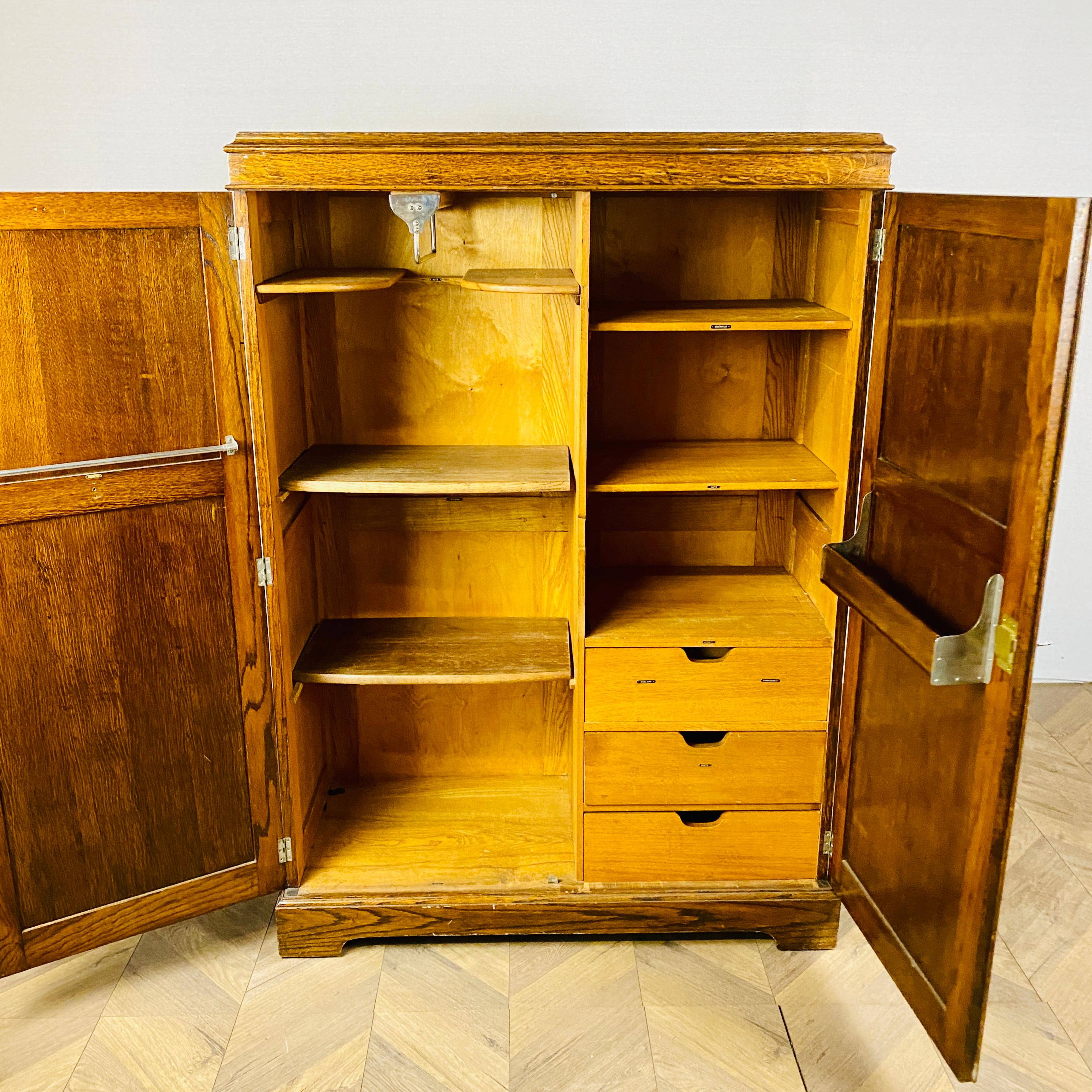 A beautiful solid English oak gentleman’s wardrobe / armoire, circa 1900s.

The armoire boasts a number of drawers, shelves and hanging rails, which all have original labels attached.

The cabinet is super heavy and well built with only minor