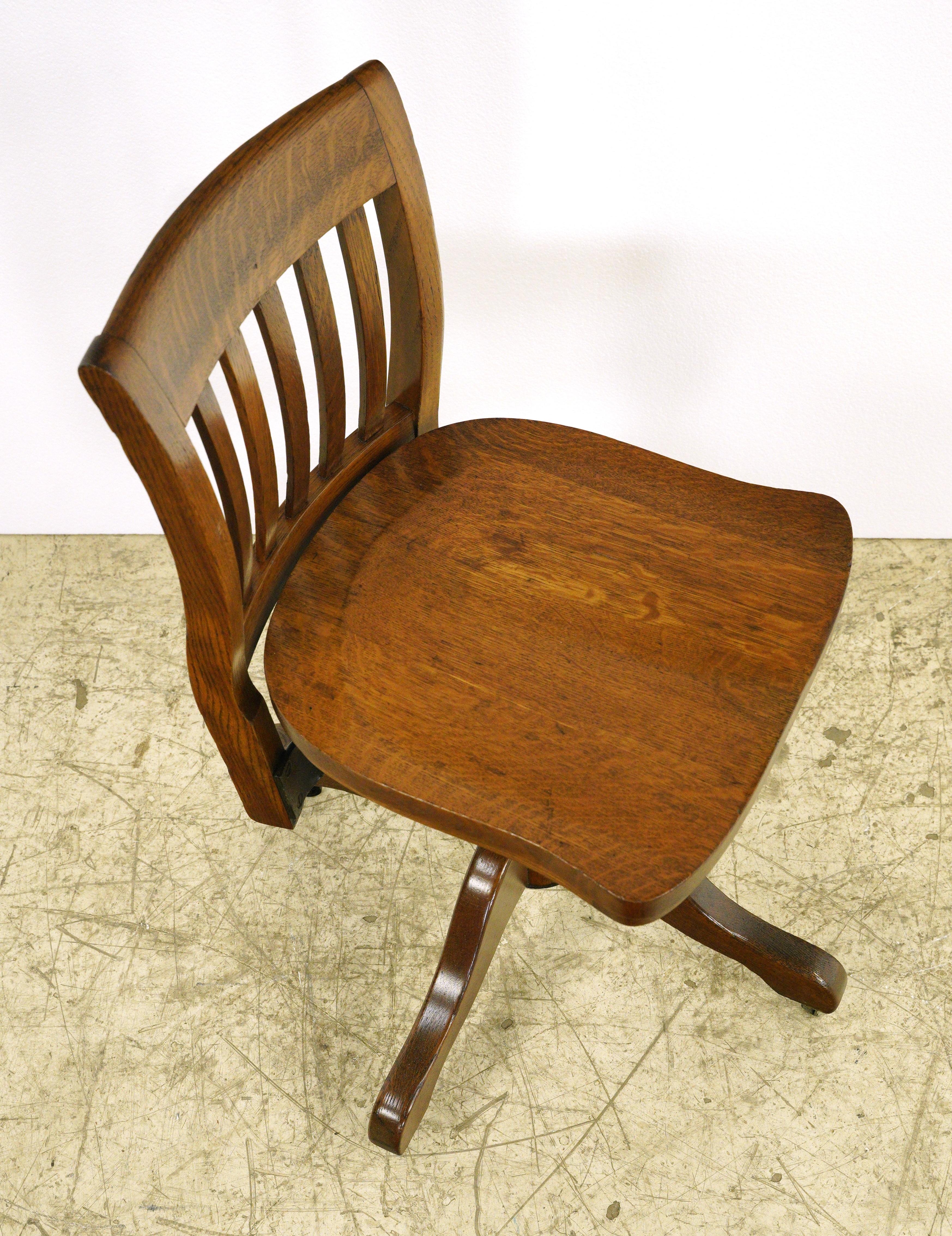 Antique solid oak desk swivel chair with a slatted back and adjustable height. Good condition with appropriate wear from age, with slight rusting on the steel hardware. One available.  Please note, this item is located in one of our NYC locations.