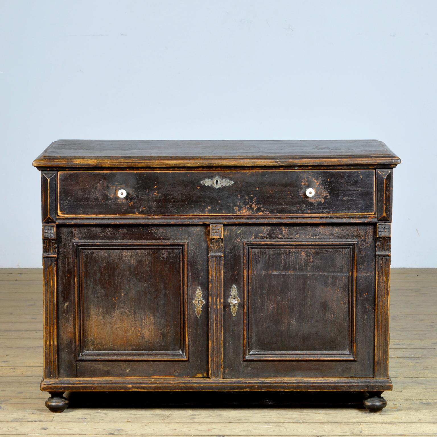Beautiful wooden sideboard from circa 1920. Made of pine. The case has its original paint with a nice patina. Beautiful frames on the doors and porcelain knobs on the drawer. The cabinet has a well-functioning lock with key. This cabinet has been