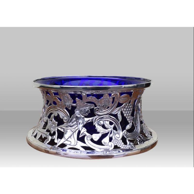 Stunning quality antique solid sterling silver dish ring / potato ring featuring a rich ornate pierced design of birds, dolphin, grapes, flowers, scrolling and figure of oriental working man.

Complete with Bristol blue liner. Dish Rings are used