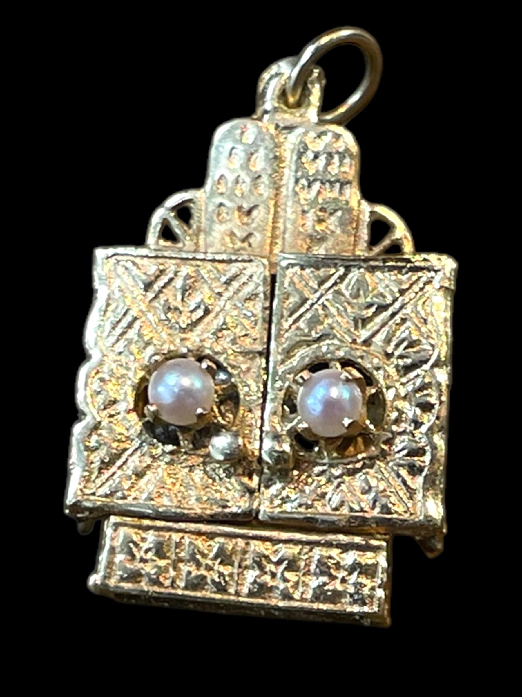 A symbol of faith and craftsmanship, this 14K yellow gold pendant/Charm is designed as an ornate Torah ark with hinged gates that open to reveal a white gold deity-like figure inside. Intricately detailed, the pendant is adorned with pearls and fine