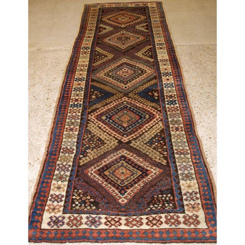 Antique South Caucasian Kurdish runner with a repeated hook medallion design.

The runner has a colourful feel with the medallions each being in a different colour, the ivory ground border is of a classic design for the region.

The runner is in