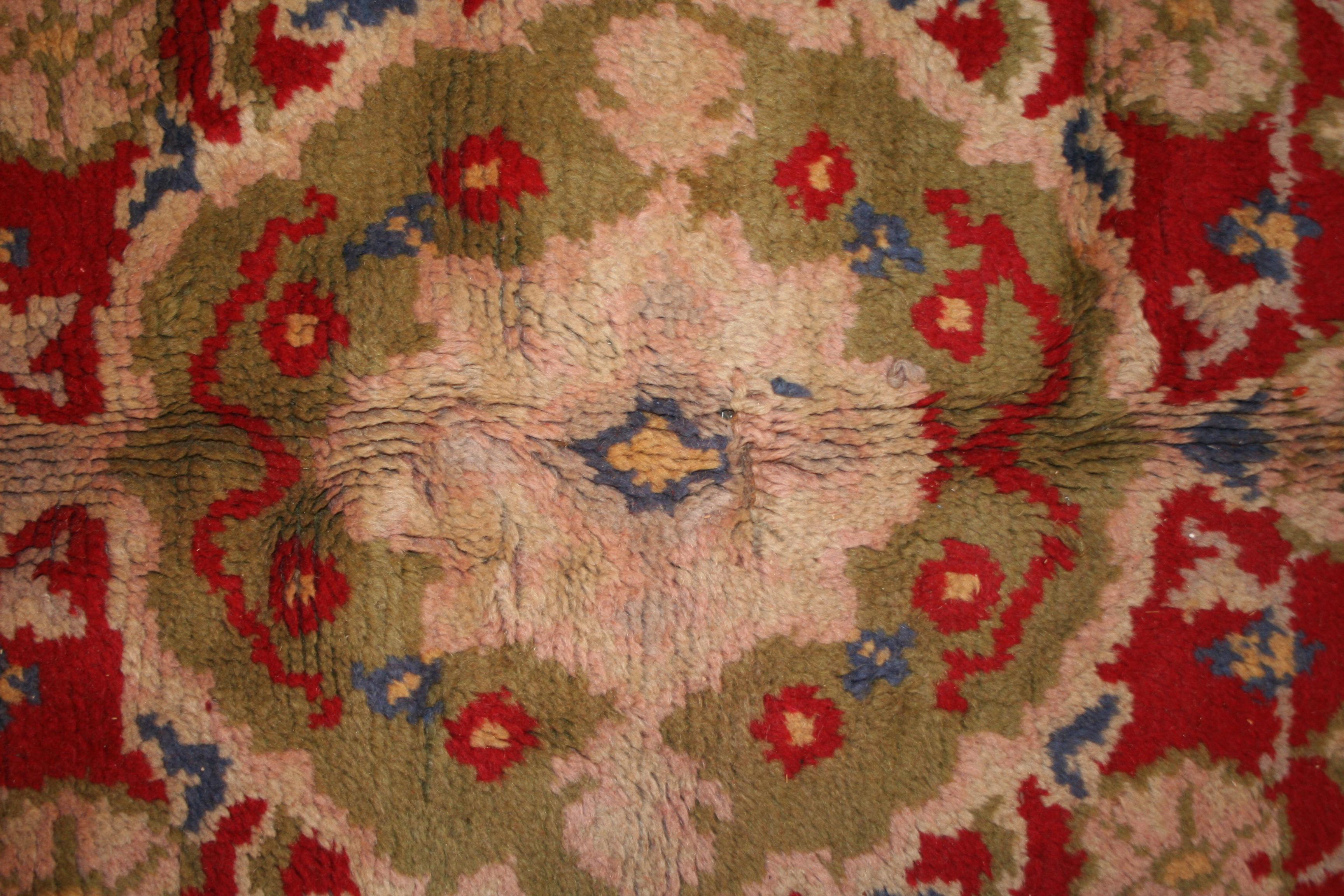 A rare and unusual Art Nouveau carpet decorated by a central medallion inspired by Oriental rugs dominating over a brilliant red open field, with paisley motifs embellishing the corners and a wide border composed of stylized paisley elements on a