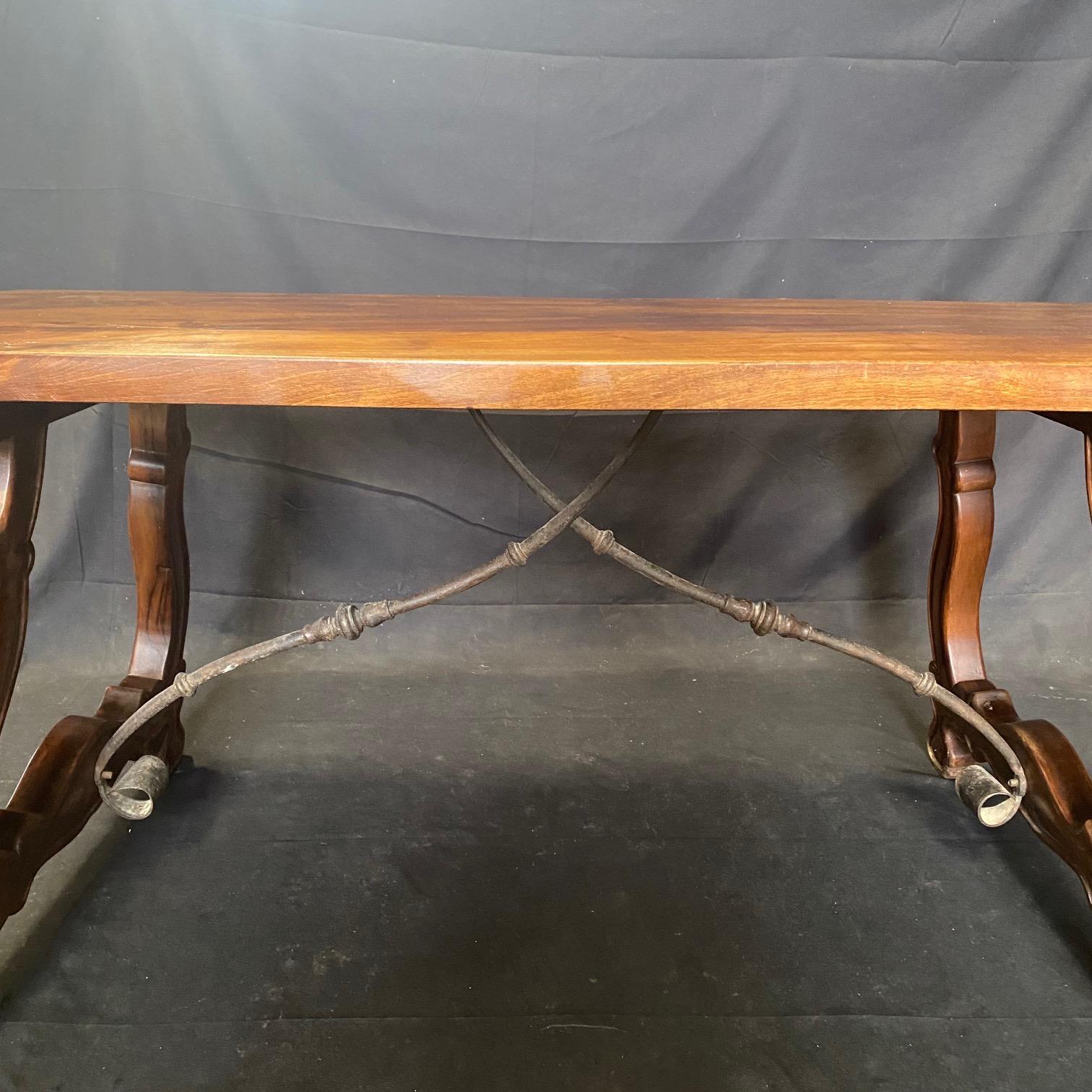 An antique Spanish baroque trestle table, having a rectangular solid walnut board top, resting on hand carved, classical lyre or 