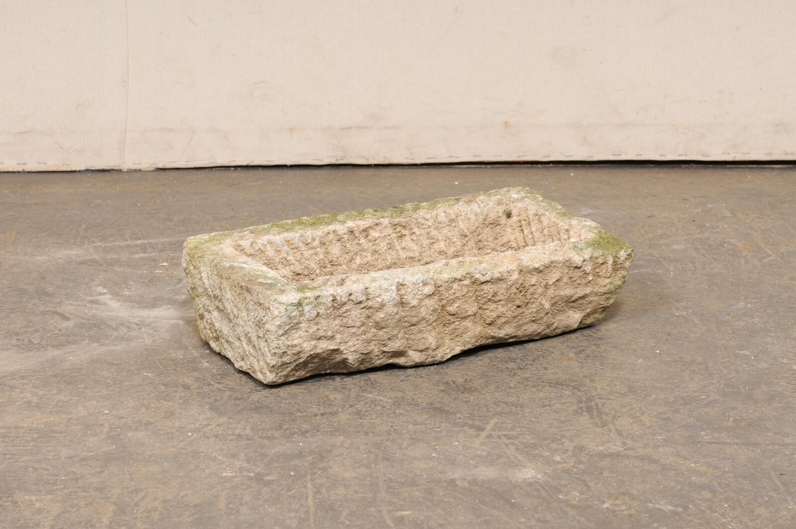 A Spanish carved stone basin from the turn of the 19th and 20th century, potentially older. This antique trough from Spain, has a mostly rectangular shape, which has been hand-carved out of a single piece of stone. The exterior and basin interior