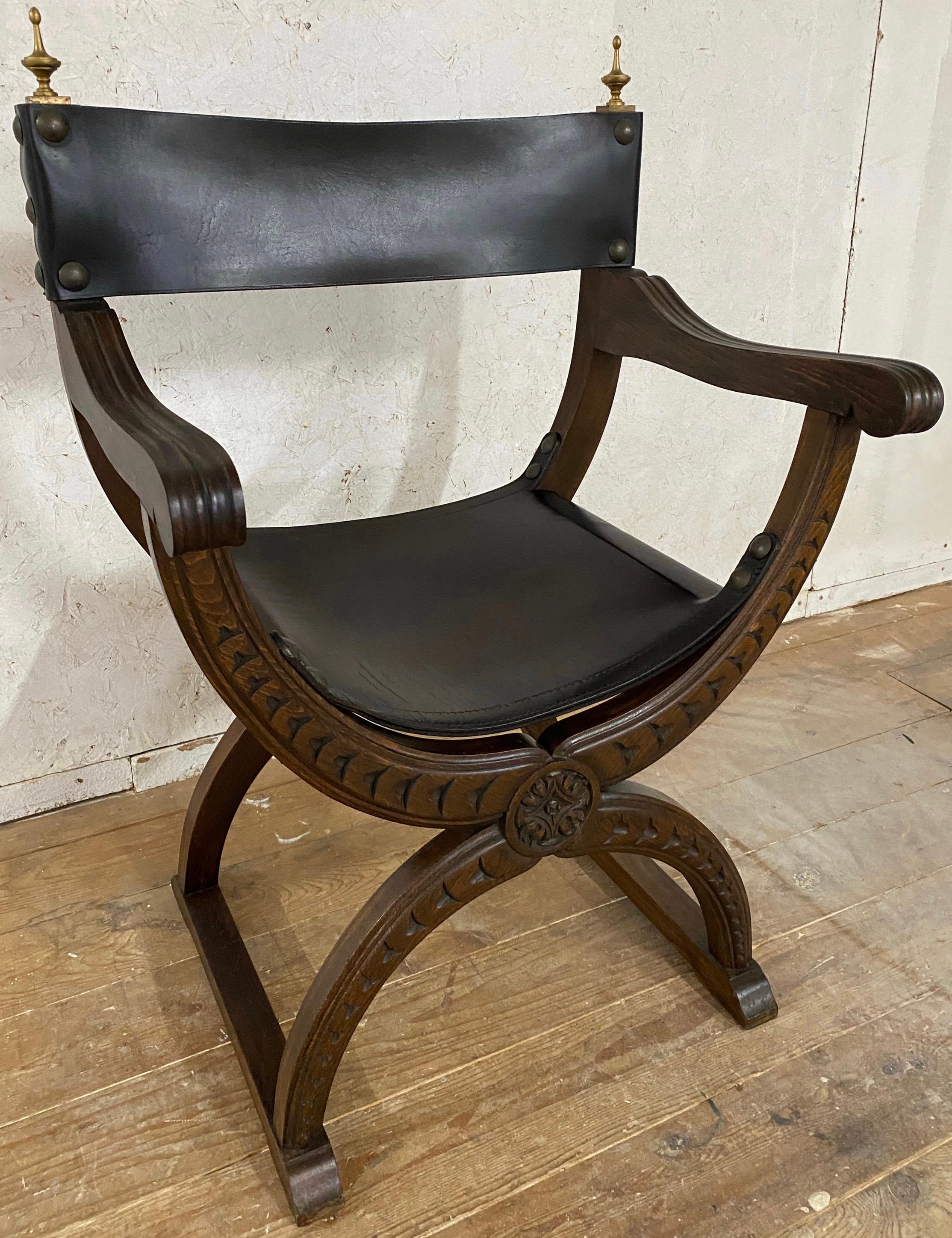 A very handsome 19th Century continental renaissance style Curule Savonarola
armchair or throne chair. This beautifully carved Gothic style chair with seat and back in black leather with large nail heads and brass urn finials. Solid carved wood