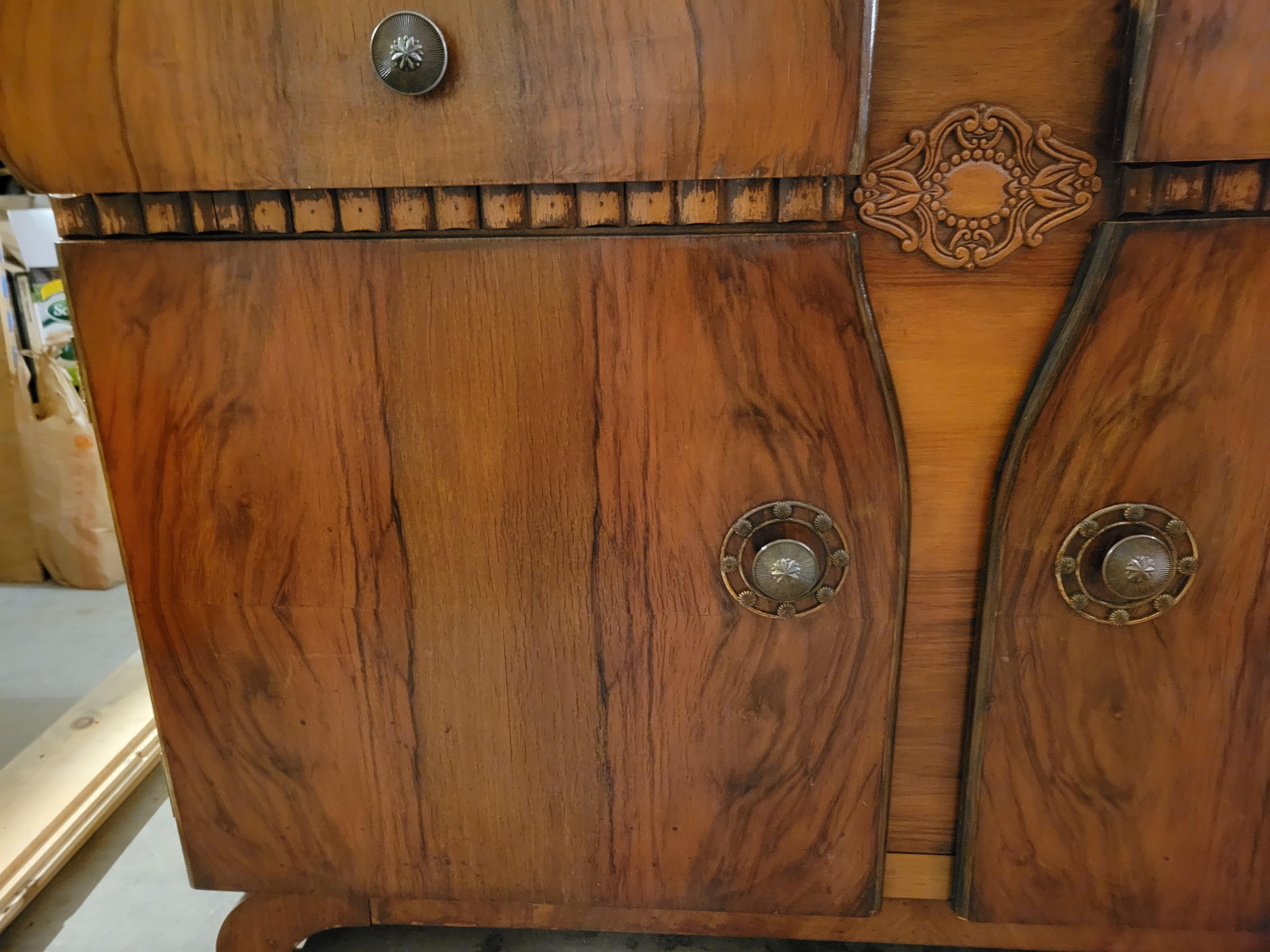 The antique chest made of solid wood and decorated with veneer. The wood is quite light and looks like walnut or birch. The chest has two drawers on top and a lower compartment divided by a horizontal shelf. The doors and drawers open and close