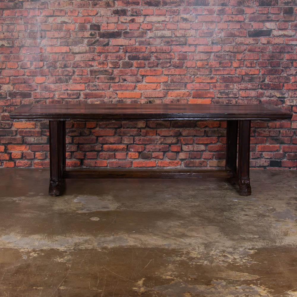 This long handcrafted dining table is stunning with it's dark hardwood top, sculpted legs and heavily carved scrolled feet. Made from a Philippine hardwood, the table has a light open feel with the hand-carved legs and trestle base. The table has
