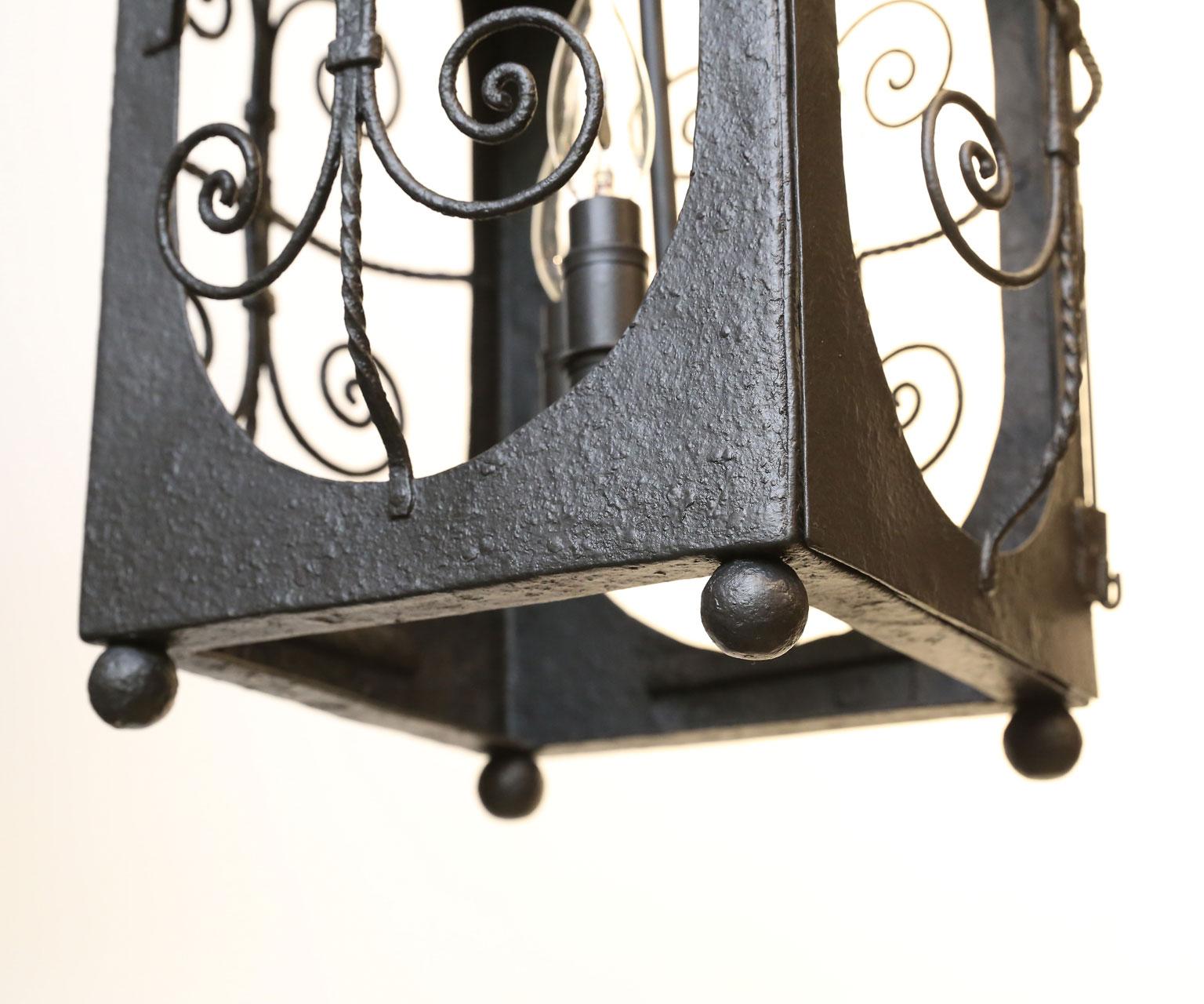 Antique Spanish Colonial lantern (circa 1920s, Spain) painted in black iron with functional panel door. Newly wired for use within the USA and sockets accommodate three candelabra-size bulbs. The lantern has a nice hand-hammered finish is is a bit
