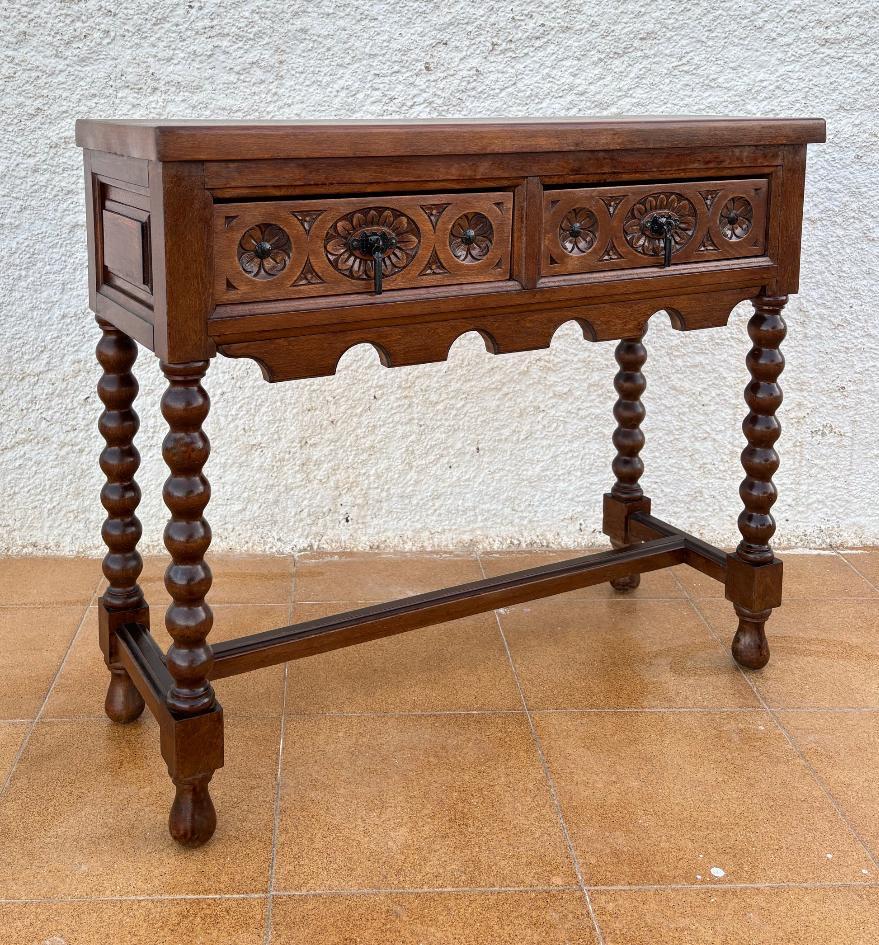 Early 20th Century Catalan Spanish Carved Walnut Console Table with Two Drawers.
This table has two beautiful carved drawers with iron handles. Its rectangular base is supported by four turned legs joined together by a straight stretcher.