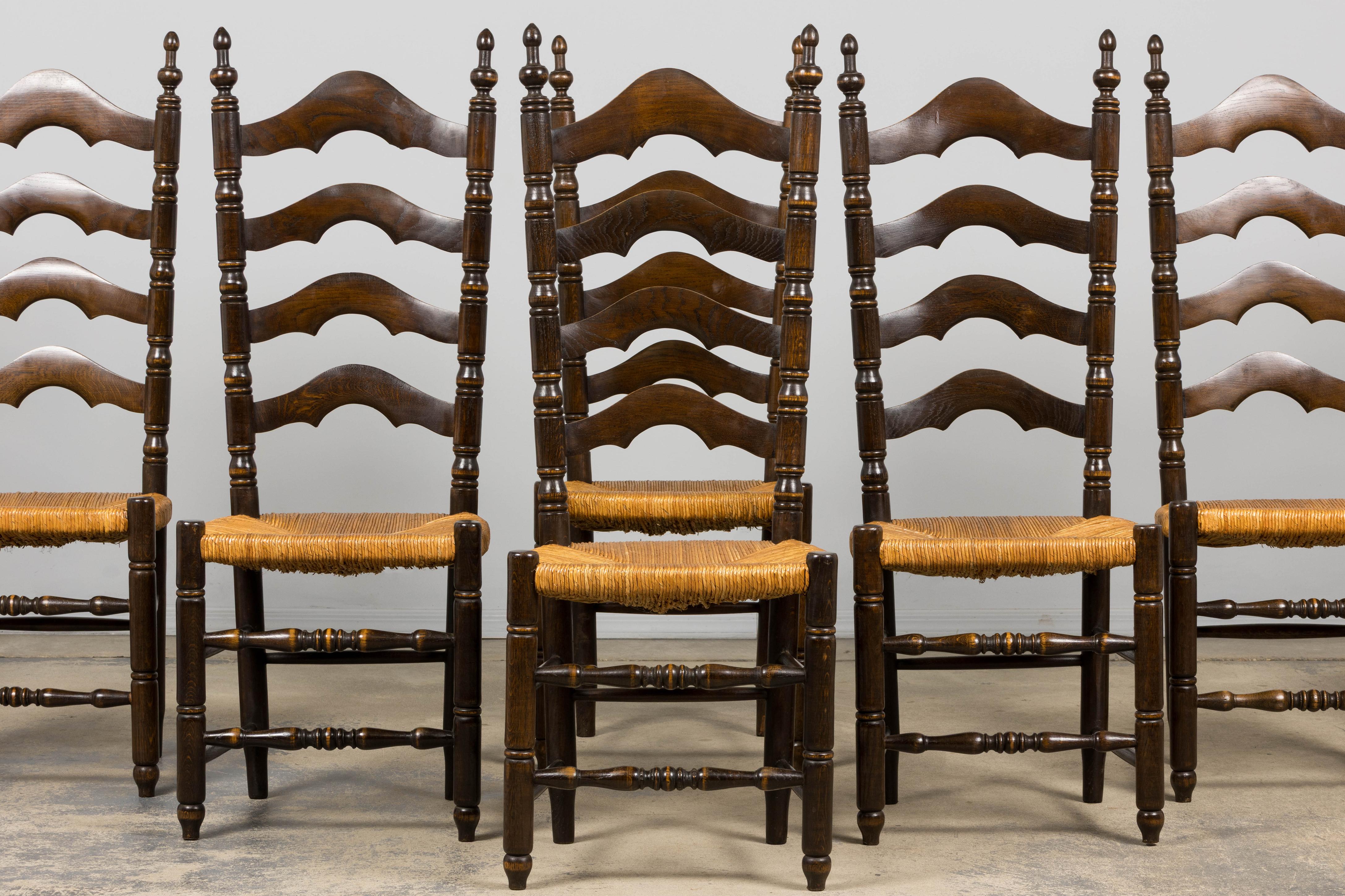 Un caratteristico set di dieci sedie da pranzo di campagna spagnola dell'inizio del XX secolo, acquistate in Provenza. Realizzata in legno massiccio di quercia, ogni sedia presenta uno schienale alto e architettonico con doghe a scaletta