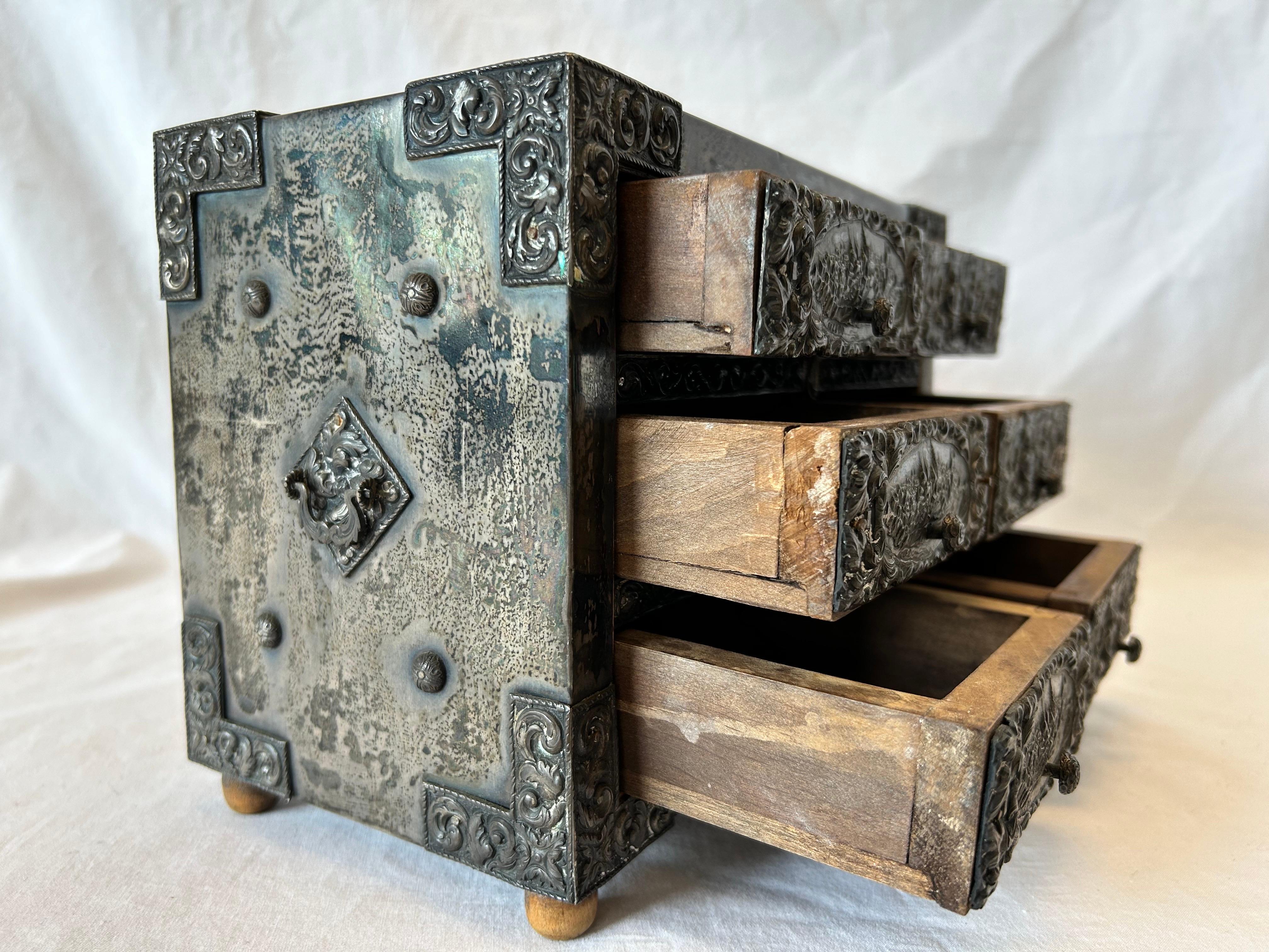 An antique, circa early 20th Century, Baroque style embossed silver clad six drawer wood casket double handled box depicting scenes of Toldeo, Spain and quite possibly the Siege of Toledo in 1085. This antique box has handles on either side, is