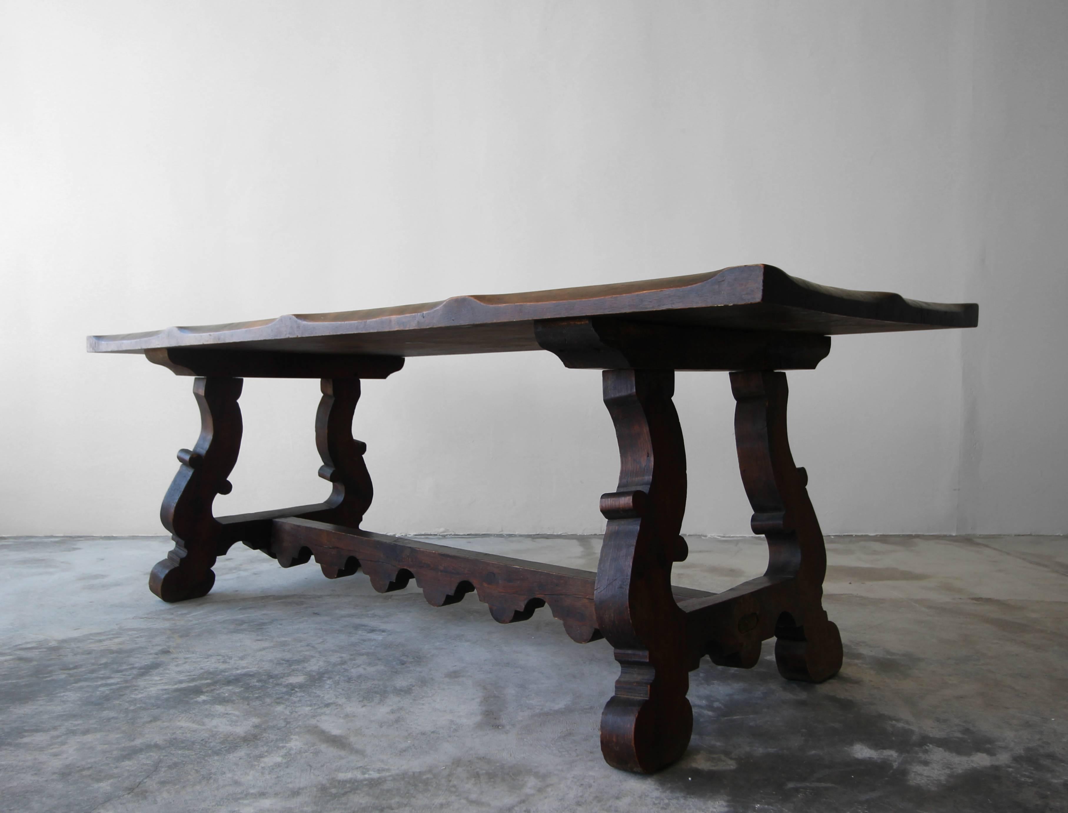 Beautiful piece with beautiful patina. This antique Spanish dining table has all the character a piece of this nature should. Constructed out of solid wood with a unique scalloped edge and carved trestle base. This truly is a stunning table in this