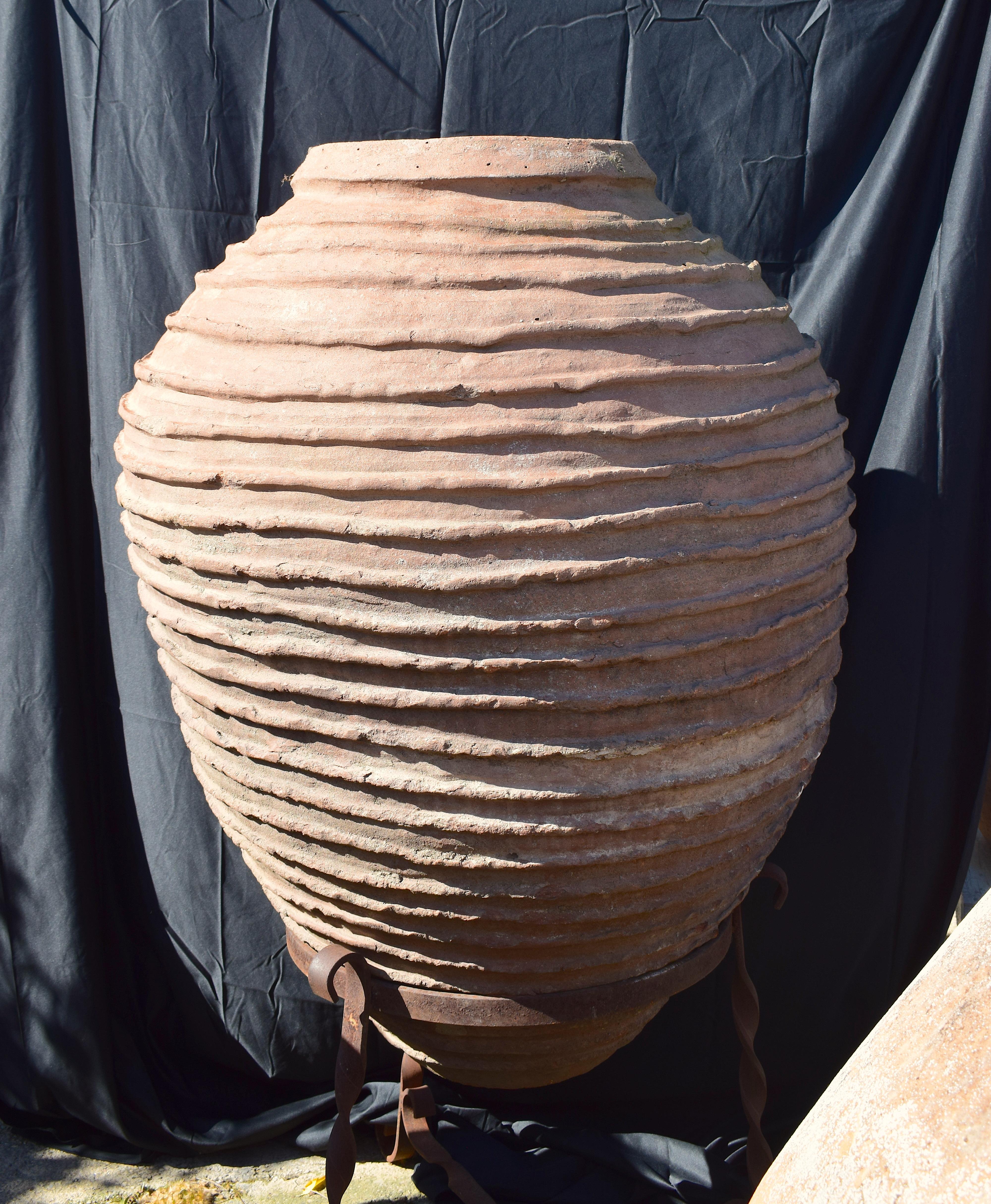 An antique Spanish large terracotta vessel from the late 19th century. This bulb-shaped vessel has thick round lips at the top opening followed by ribbed trimming around the perimeter of the exterior of the vessel. The base has a slight curve shape.