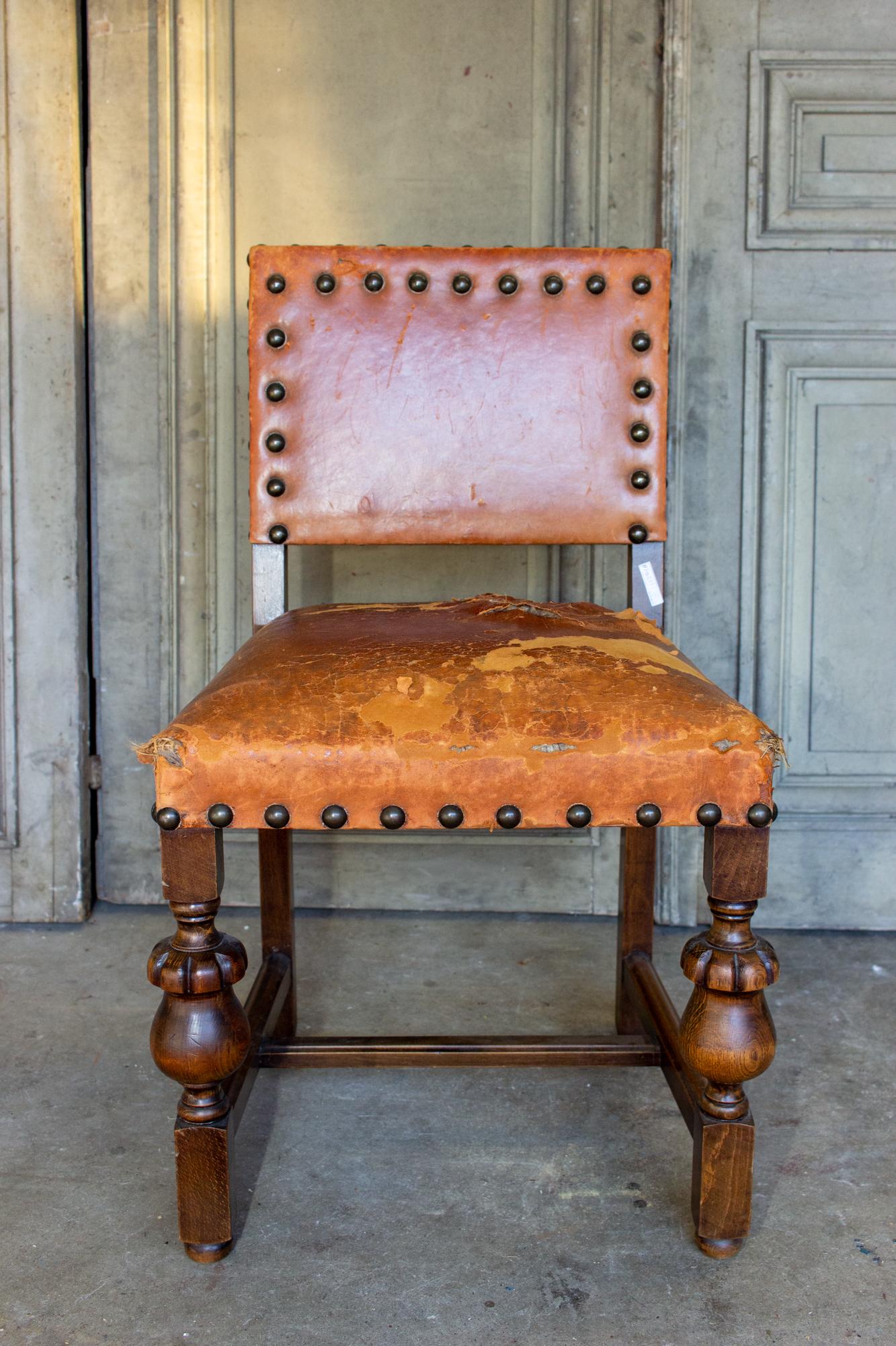 This is an antique Spanish wood & leather chair with beautiful carvings in the frame and patinated brass nailhead details. The leather is a rich deep cognac color and does have wear, patination and there is a tear on the seat. The oversized brass