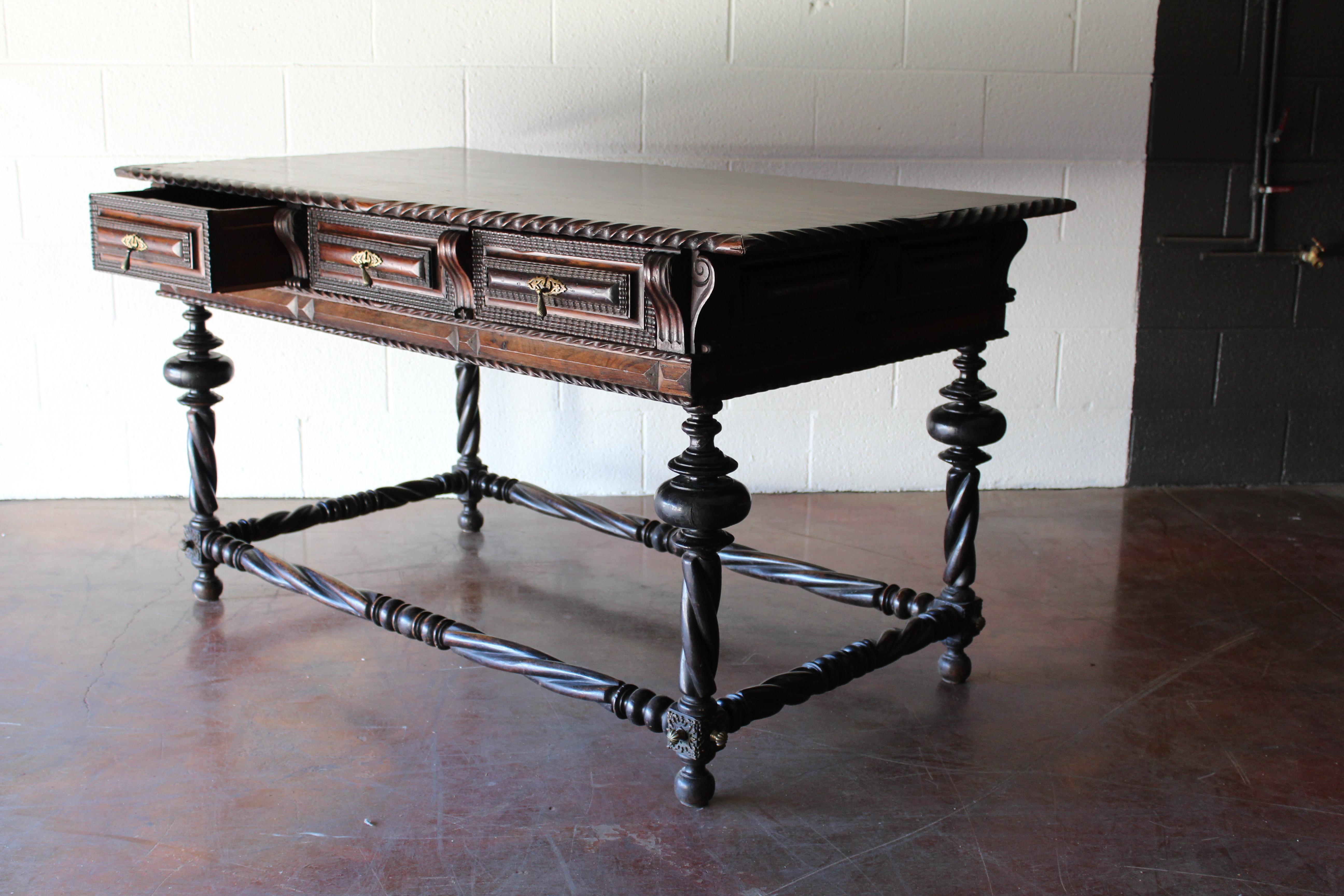 18th century Portuguese library table, with three drawers. Intricately carved walnut with bronze hardware and corner details.
