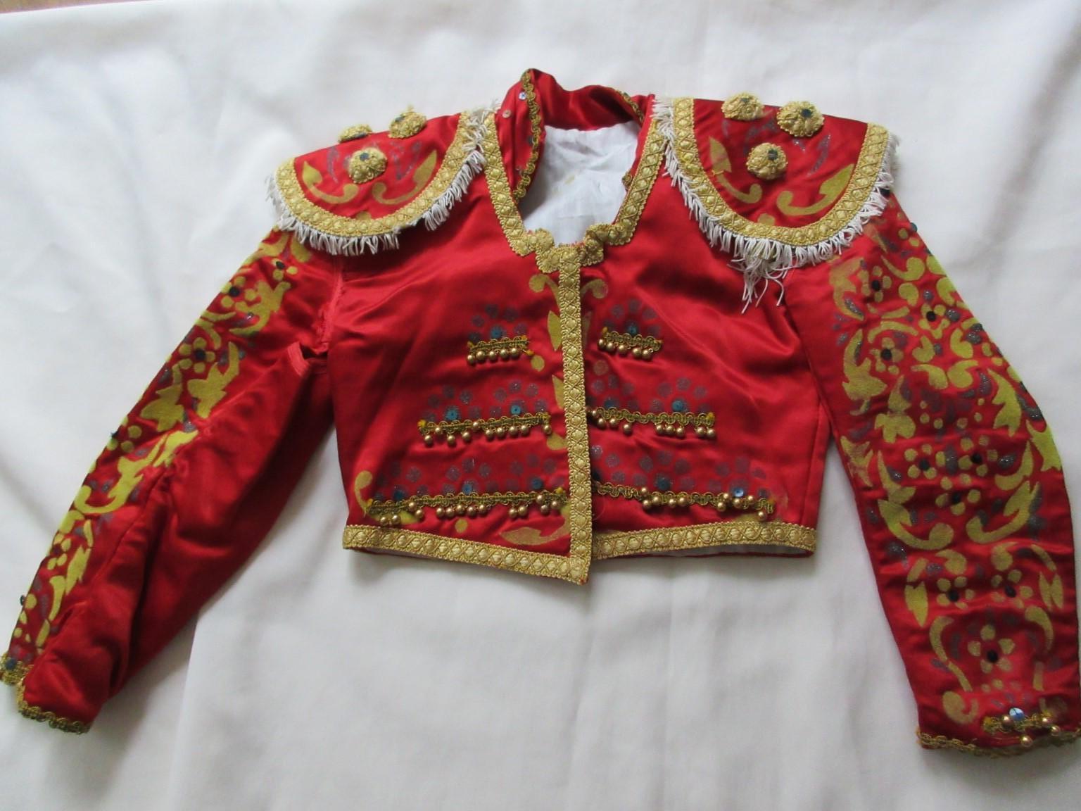 This is an unique antique toreador jacket, Traje de Luces with 
black torero head ( Montera, capa de brega)

We offer more exclusive vintage items, view our frontstore.

Details:
Color and material: red silk with yellow/gold embroidery and darkgold