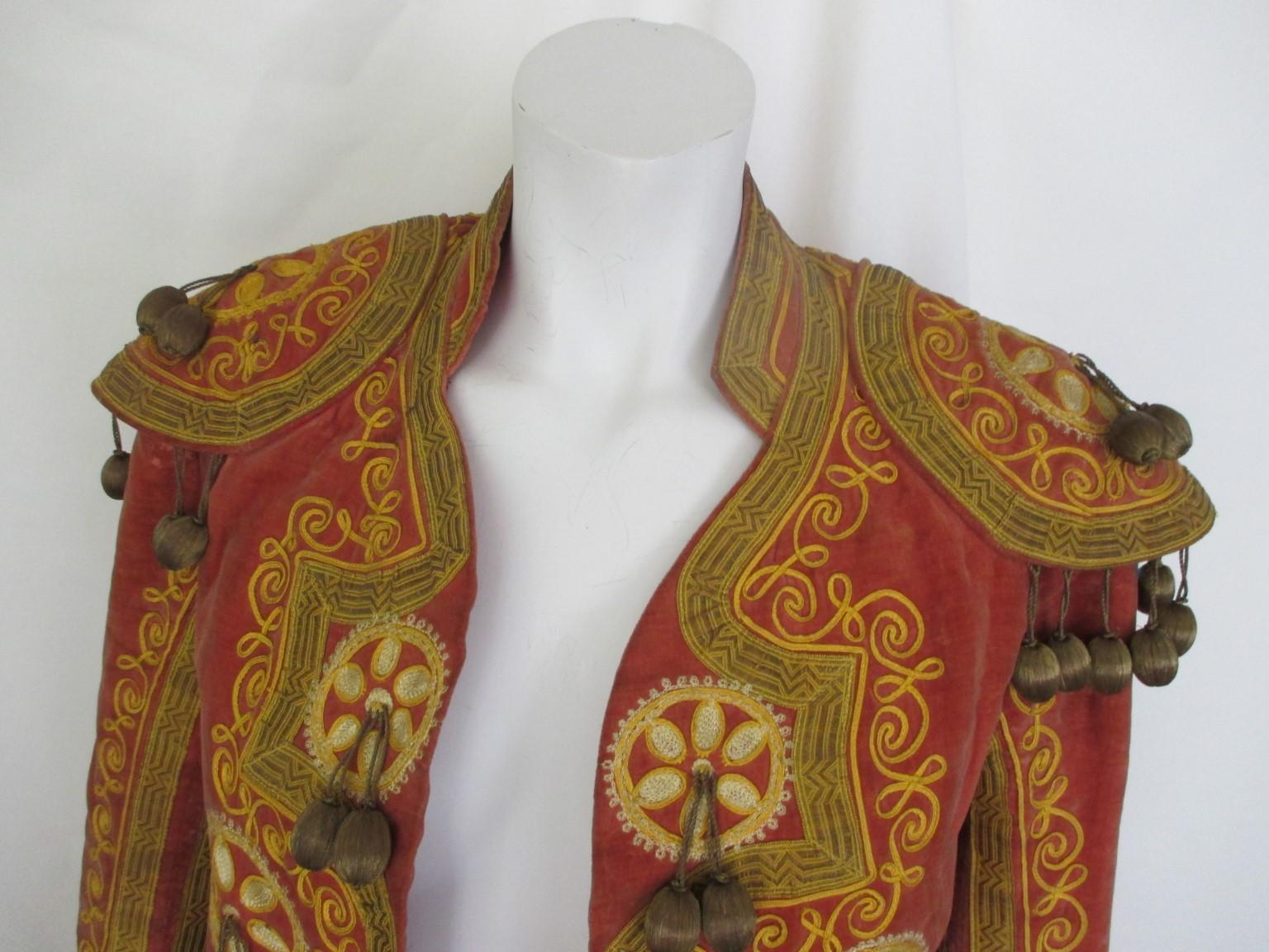 This is an unique antique handmade toreador jacket, Traje de Luces

We offer more exclusive vintage items, view our frontstore.

Details:
Color and material: soft pink velvet with yellow/gold embroidery and darkgold 
tassels ( some are