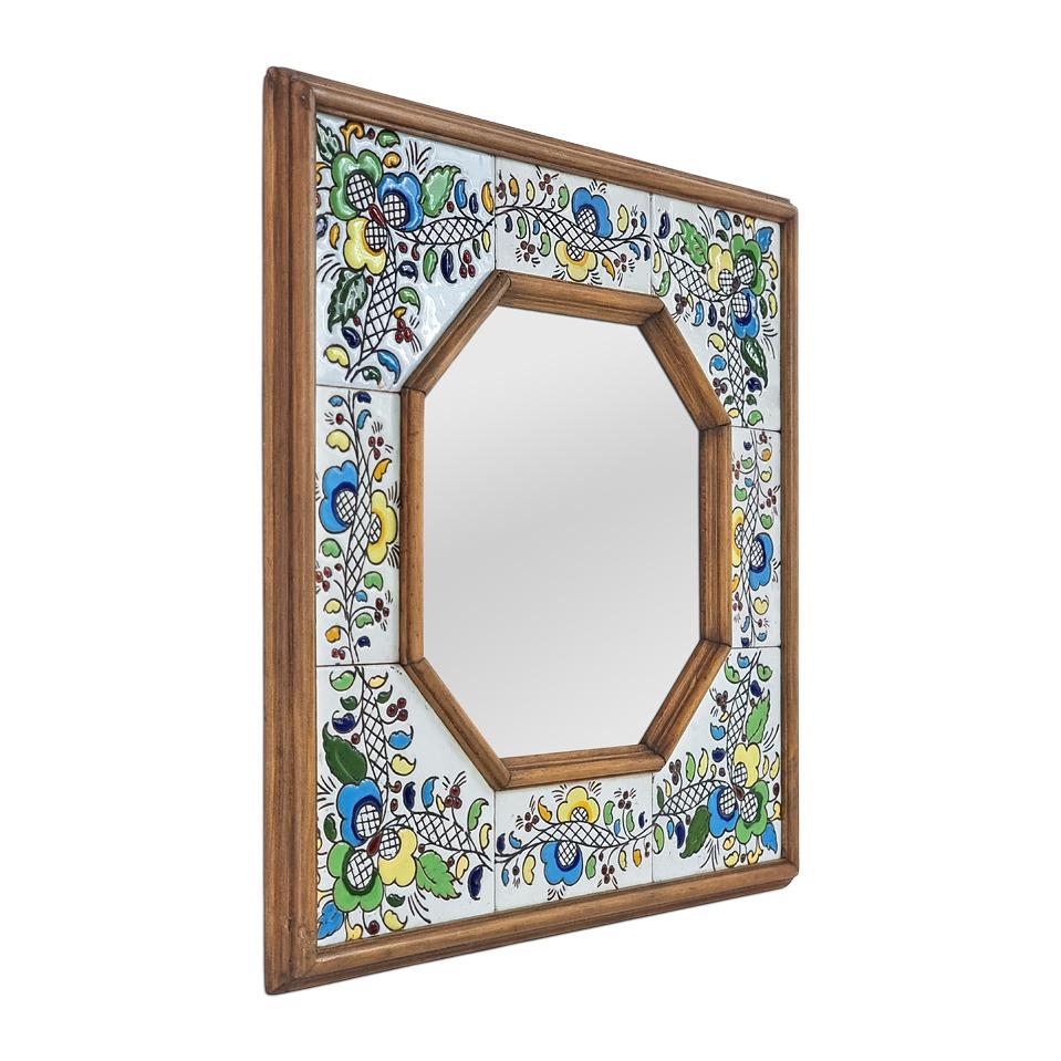 Antico specchio da parete quadrato spagnolo in ceramica e legno tinto, degli anni '60. Ceramica bianca antica con motivi floreali multicolore. Larghezza del telaio:  11,5 cm. Specchio moderno in vetro ottagonale. Pannello posteriore in legno.