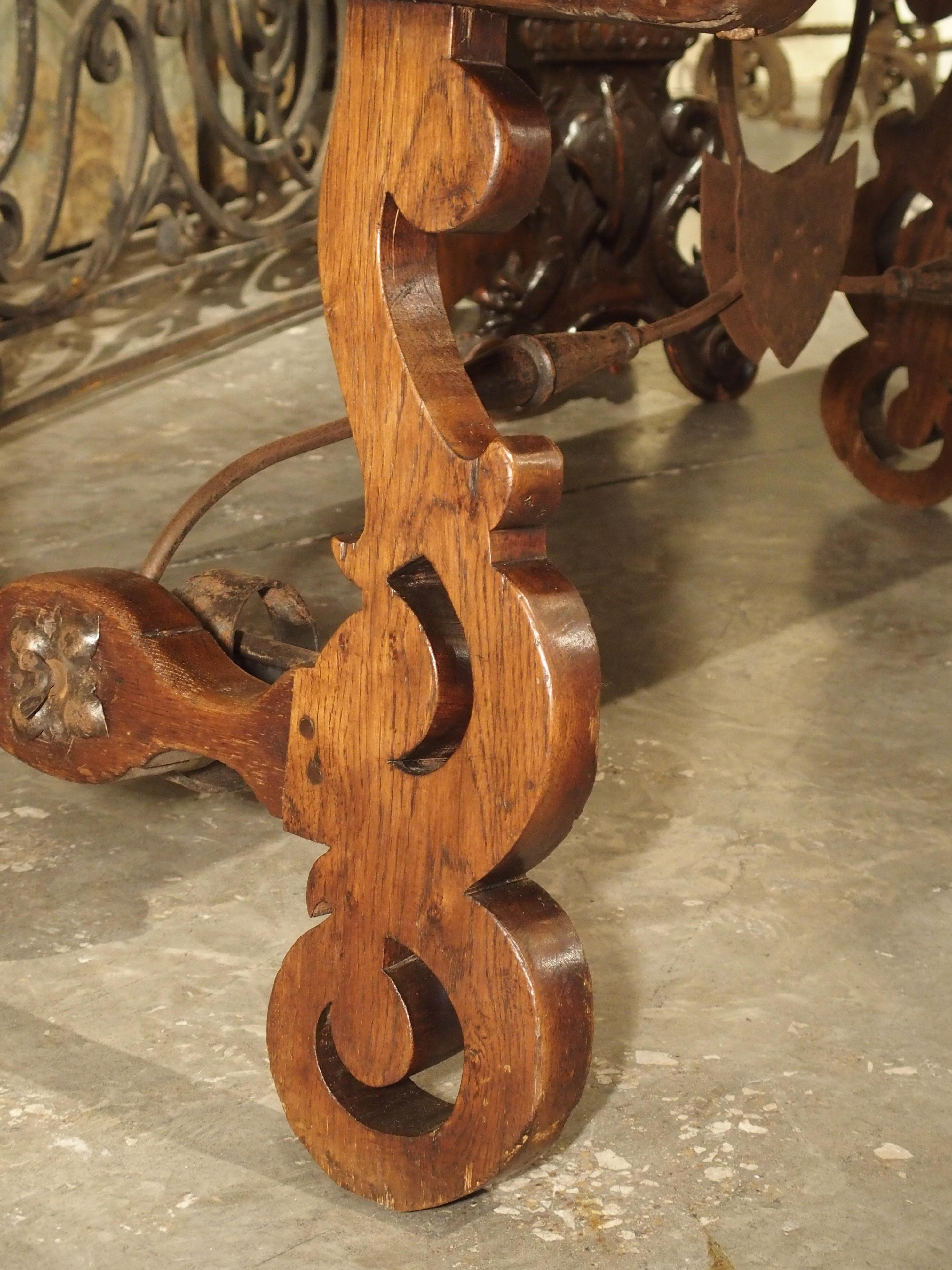 Made in Spain, circa 1900, this oak table with lyre legs has a unique wrought iron stretcher.

An unadorned oak tabletop (which is often seen in Spanish tables) is offset by open lyre legs hand carved with ornate volute scrolls. The legs are