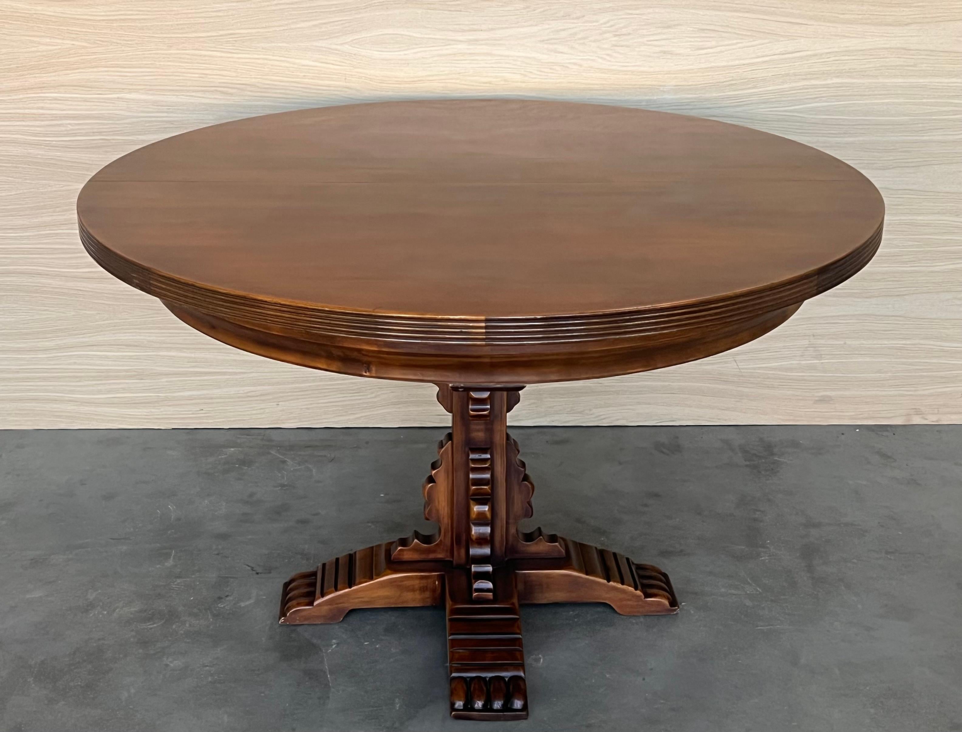 An antique Spanish Carved Walnut pedestal dining table. Circa 1900. Having a round top over a beaded skirt, rising on a pedestal, four stretches on the raised base to reinforce the table.

The leaf adds 17.71in to the total large.