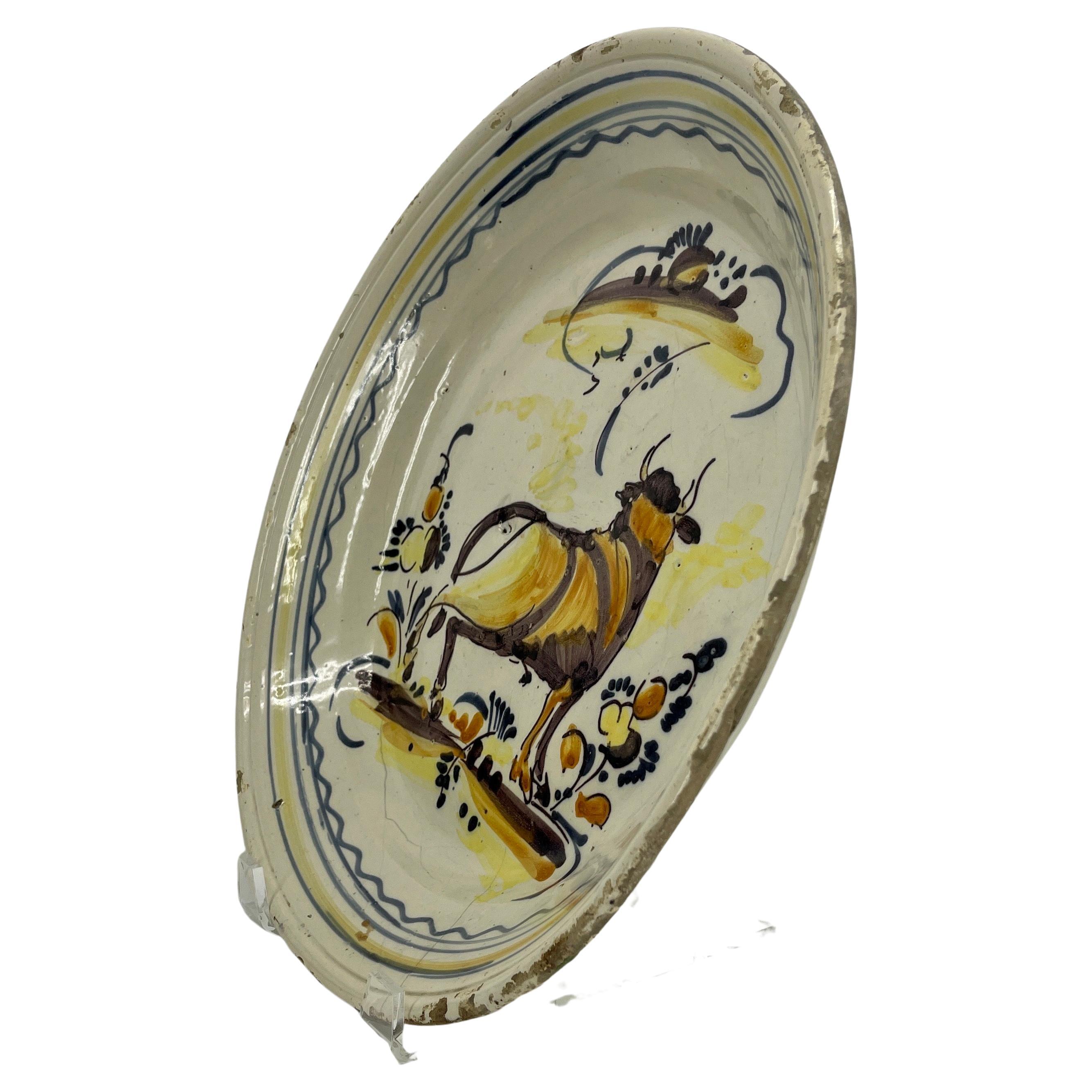 Circa 1800 Spanish Majolica Faience centerpiece bowl or charger.
This charming collectible antique painted ceramic dish is decorated with a large rear facing bull and with polychrome flowers.
  