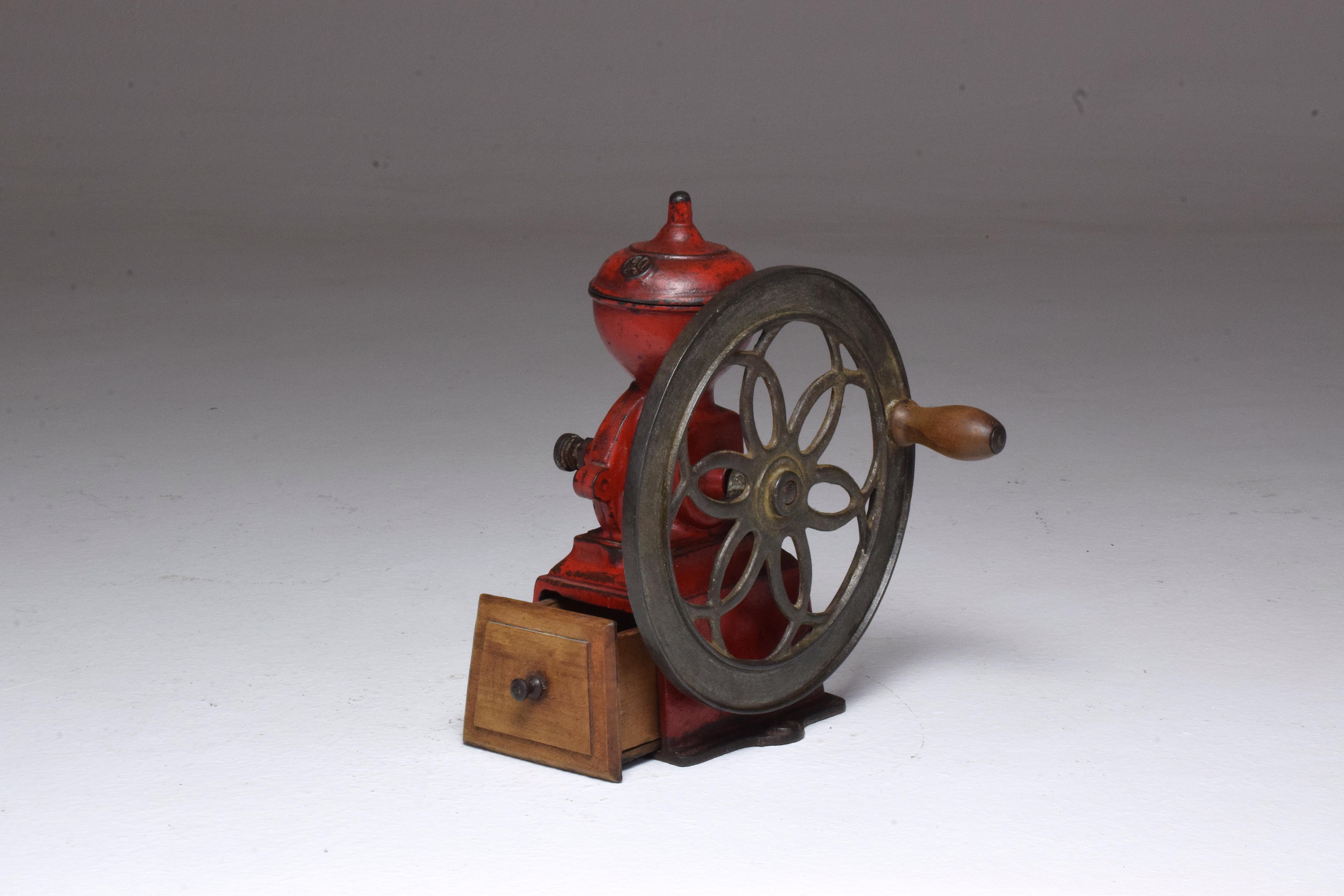 Antique Spanish coffee wheel-type grinder from the basque area of Spain, circa 1910s- 1920s. It is composed of red painted cast iron with handle and drawer made of light wood.
A unique decorative or utility piece for kitchen, bar or living room or