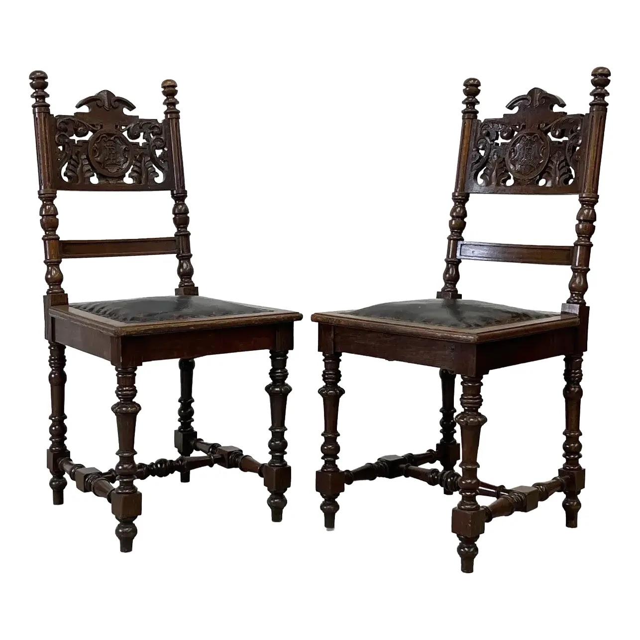 Paar antike, geschnitzte Eichenbeistellstühle mit Wappenmotiv und Ledersitzen aus der Zeit der spanischen Wiedergeburt.
Jeder Stuhl verfügt über eine hohe, handgeschnitzte Rückenlehne mit zentralem Wappenmotiv, flankiert von Gerstenkornpfosten und