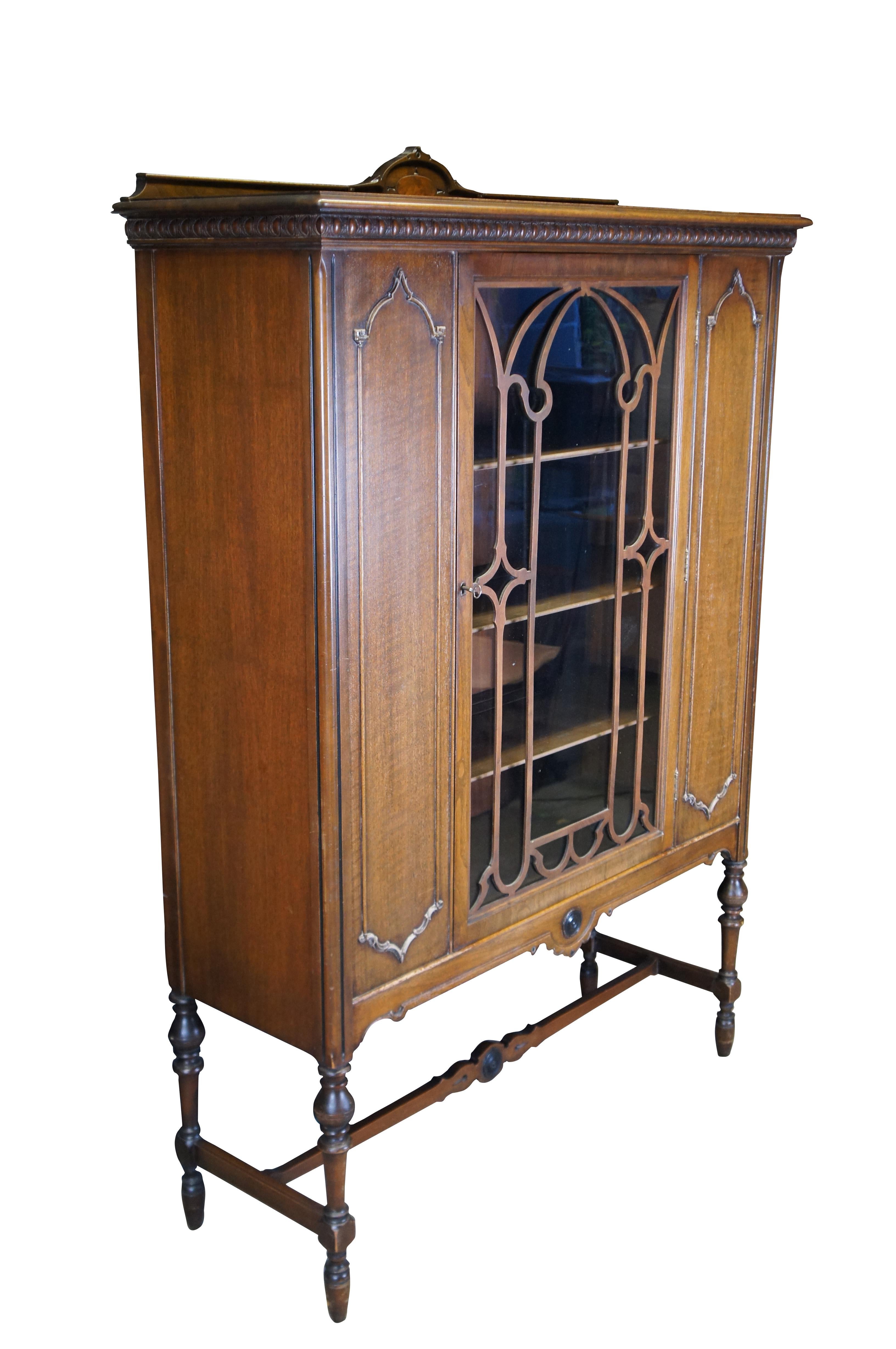 Vitrina de porcelana antigua.  De madera de nogal, con estilo gótico/español, puertas caladas, molduras de huevo y dardo, detalles en paneles, panel posterior con panel burilado y patas torneadas unidas por un travesaño en forma de