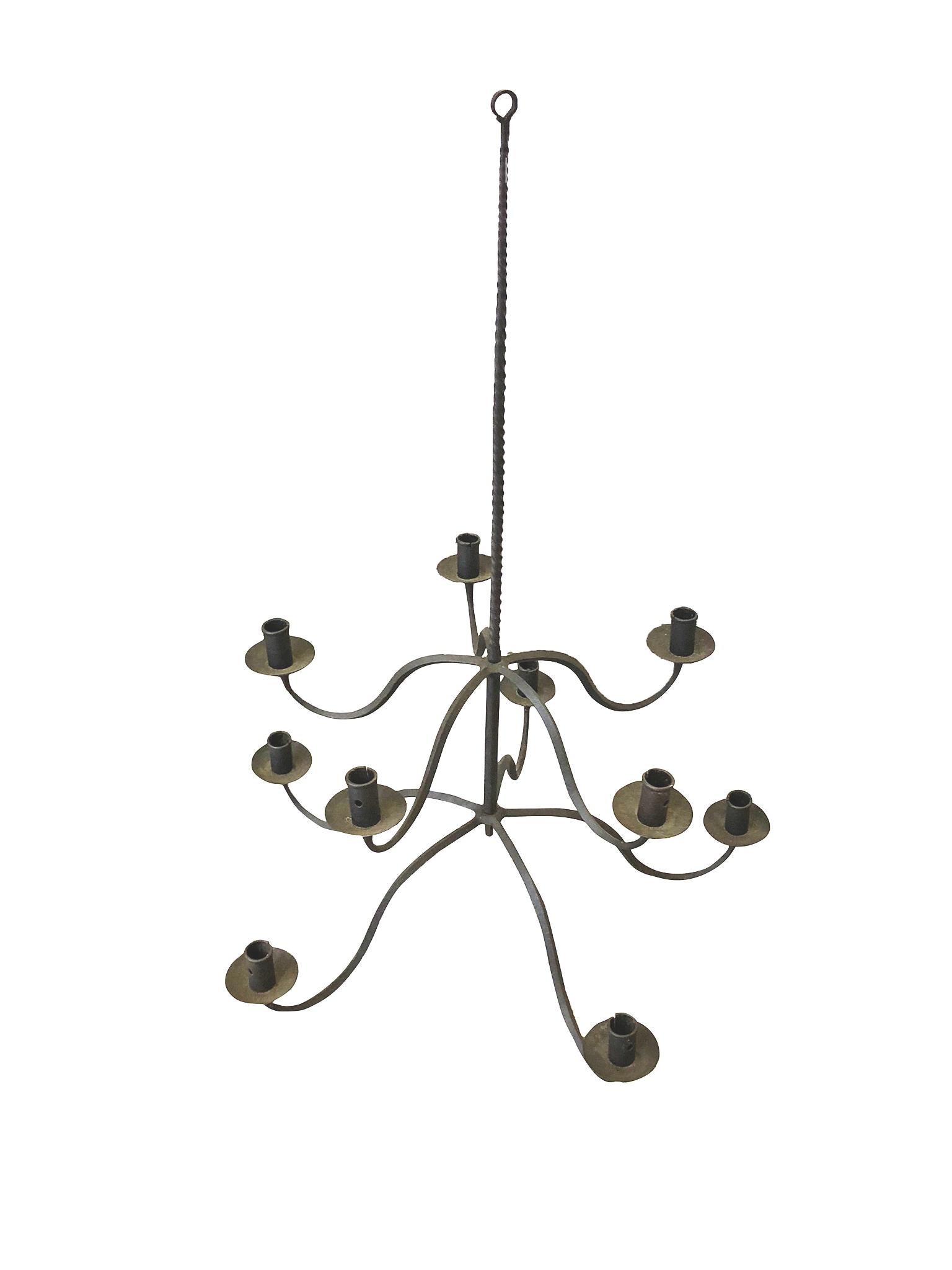 A simple, Spanish style hand forged candelabra, late 19th century. Two-tiered, with each tier comprising of 5 arms that curve down and up to the candle pans and holders. Long wrought iron stem.

Dimensions:
24 in. diameter
36 in. height.