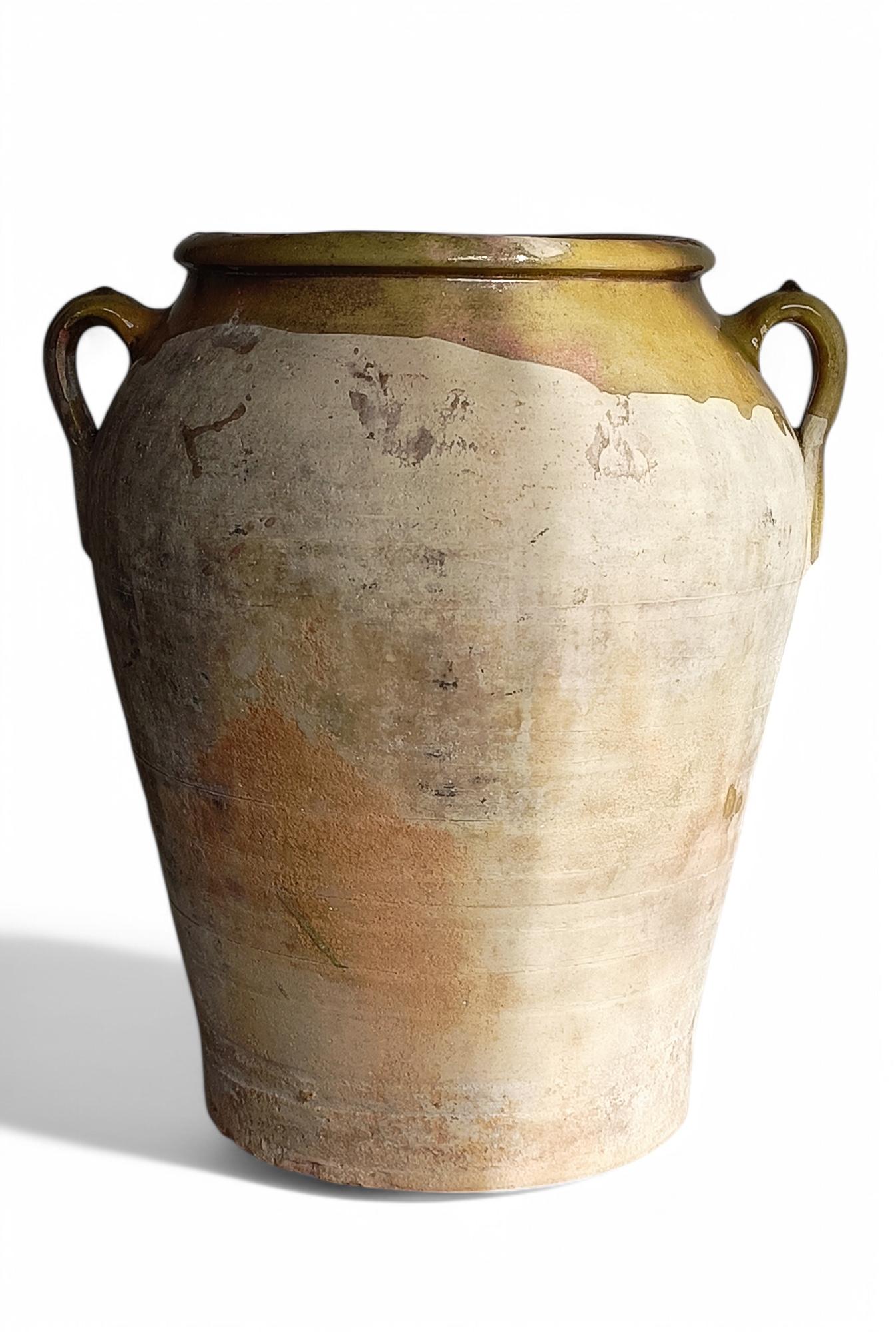 An antique large Spanish terracotta olive oil handled jar or vase, handmade towards the end of the 19th C. or beginning of the 20th C. 

The outside features the natural earth-ware color with a beautiful patina, and some olive green color glazing