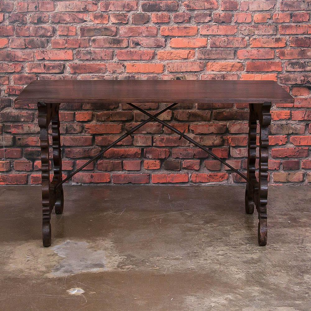The dark, rich walnut patina compliments the Spanish styling of this Fine writing table. Take special note of the ornate scrolled and splayed legs supported by iron braces giving this piece a light and airy feel, yet very sturdy at the same time.