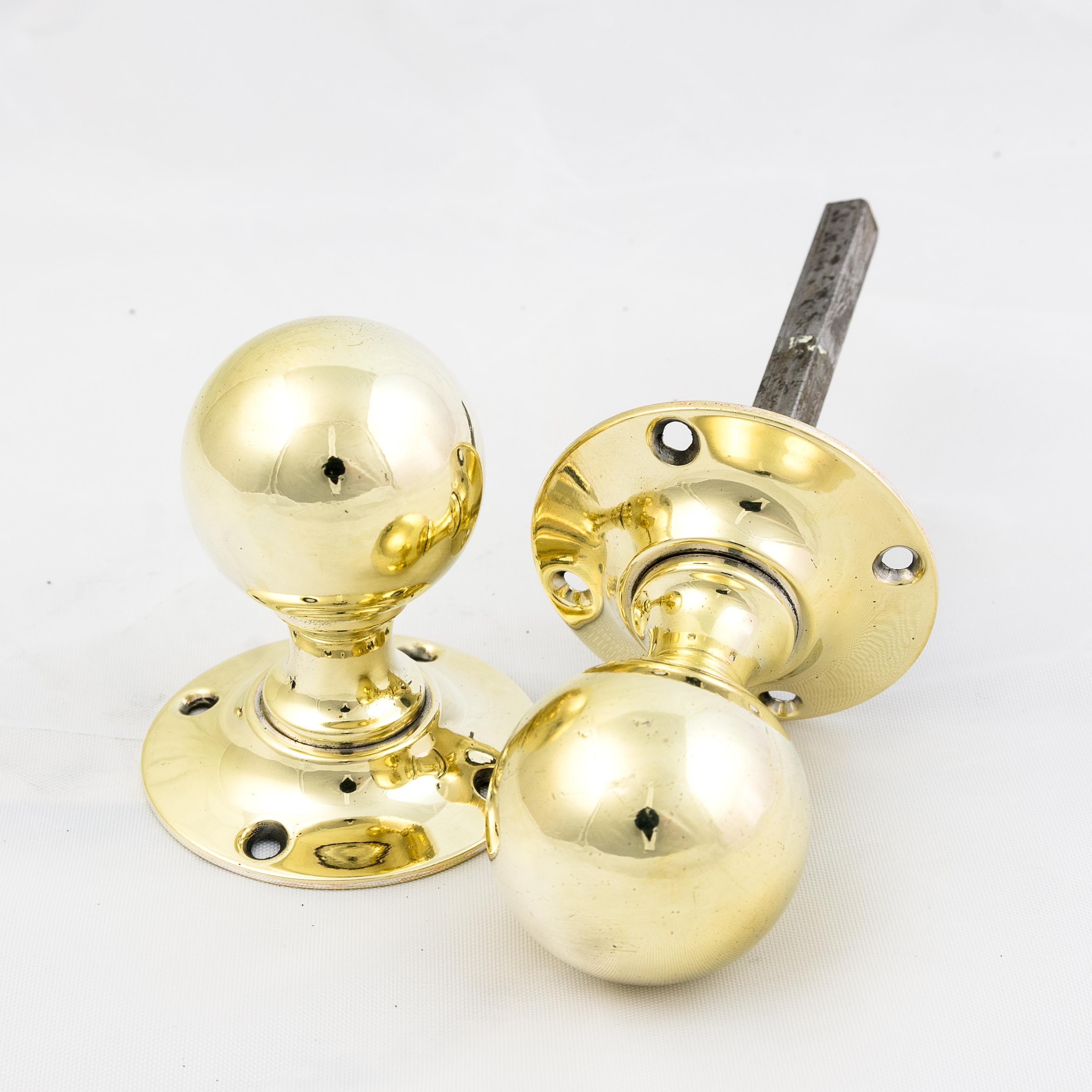 Antique spherical brass door knobs, circa 1900, with circular back-plates. Seven pairs available.