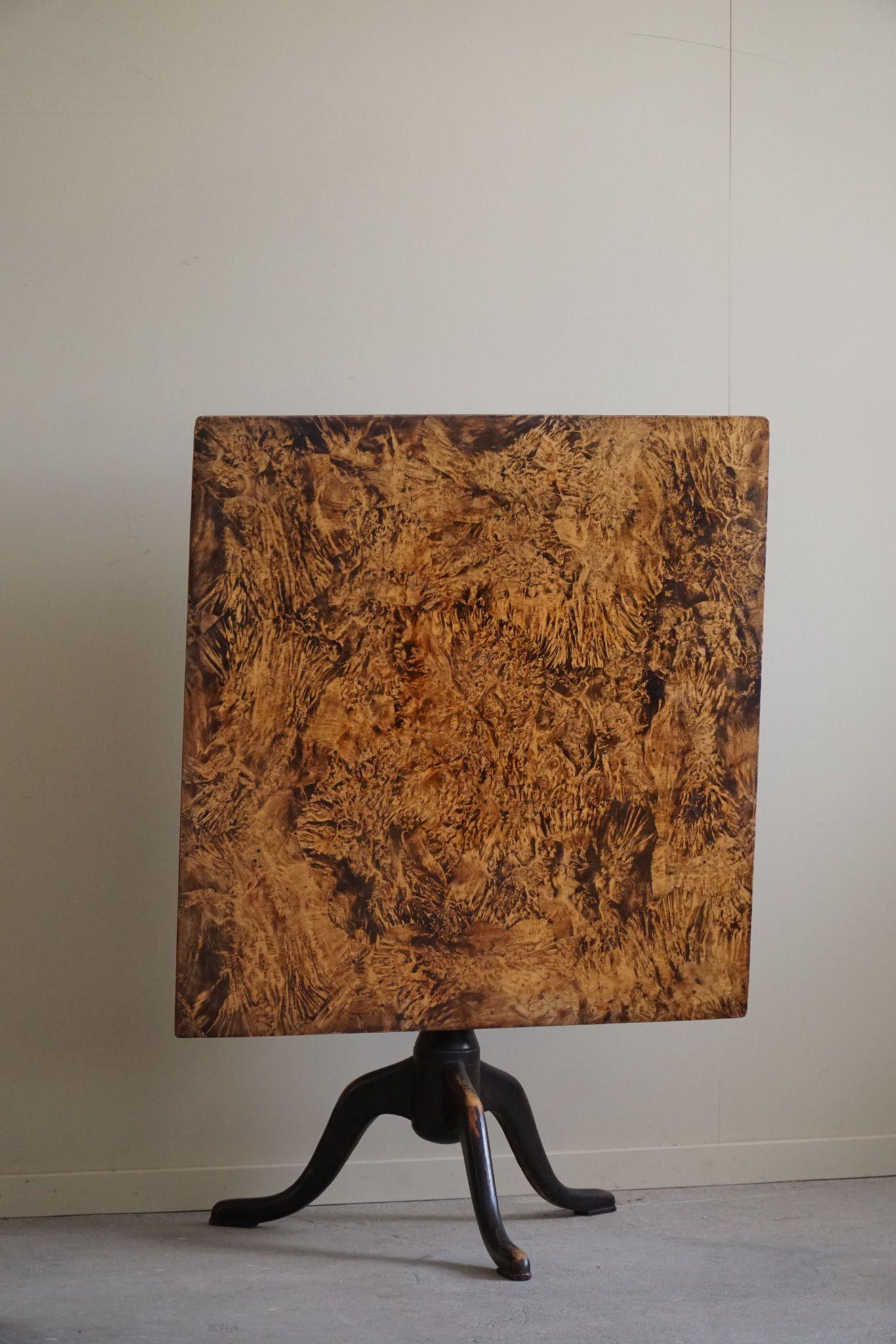 This exquisite antique square drop-leaf table is a stunning example of early 19th-century Swedish craftsmanship. Handcrafted by a skilled Swedish cabinetmaker, this table showcases the remarkable beauty and intricate detail that burl wood is