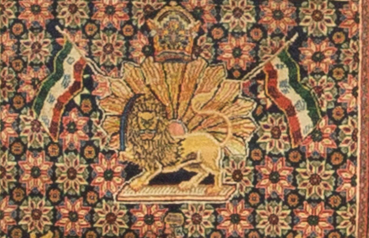 An antique Persian Kazvin rug featuring the lion and sun motif that was the best known symbol of Iran up until the revolution in 1979. The flag of Iran appears either side of the sun and this representation appeared on the pre revolutionary flag.