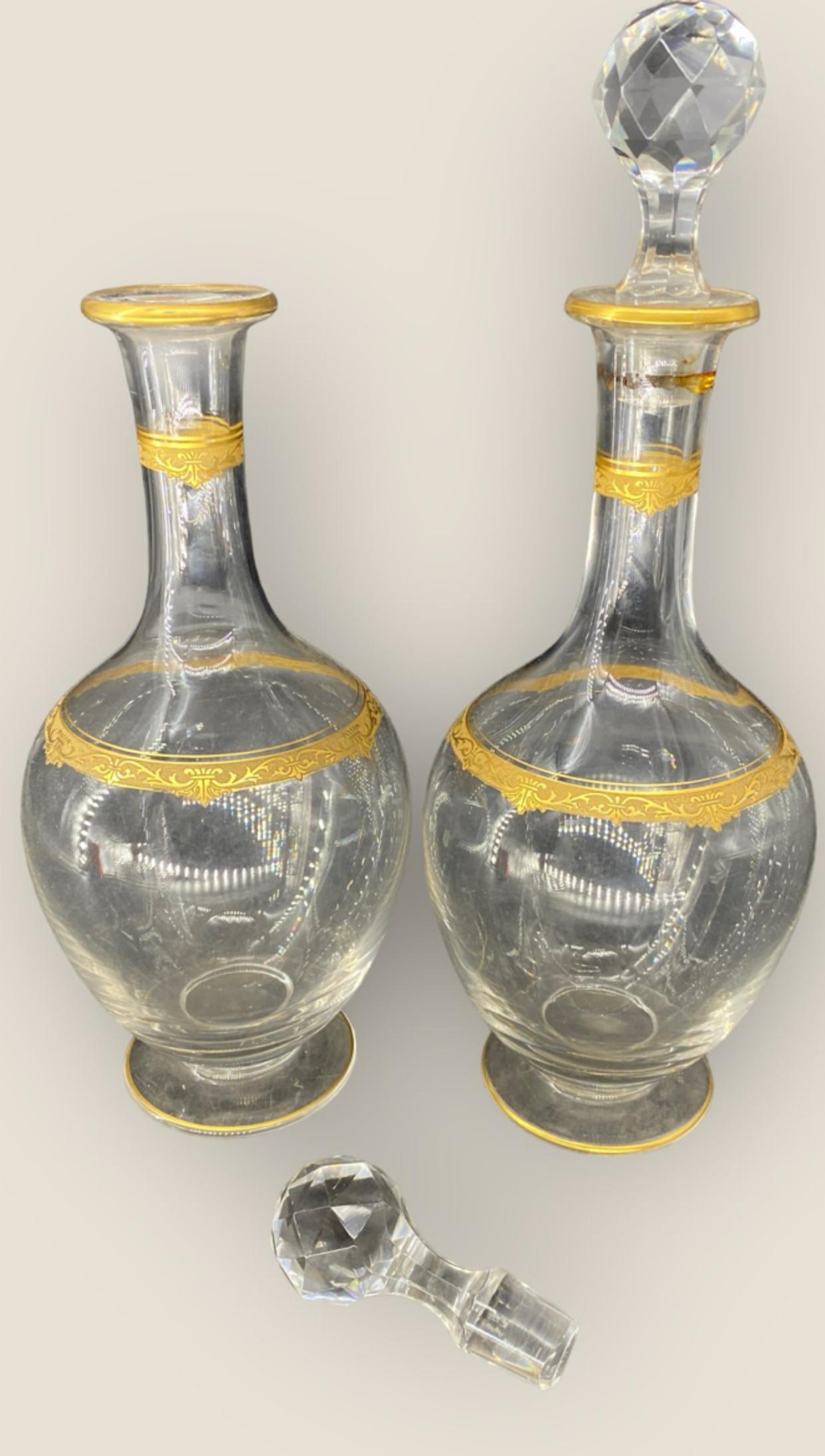 Pair of crystal, mouth blown glass decanters with gilt appointments by Saint Louis Cristallerie Glass Company. 
The Compagnie des Cristalleries de Saint-Louis is a French crystal manufacturer that designs decorative items, tableware, lights, and