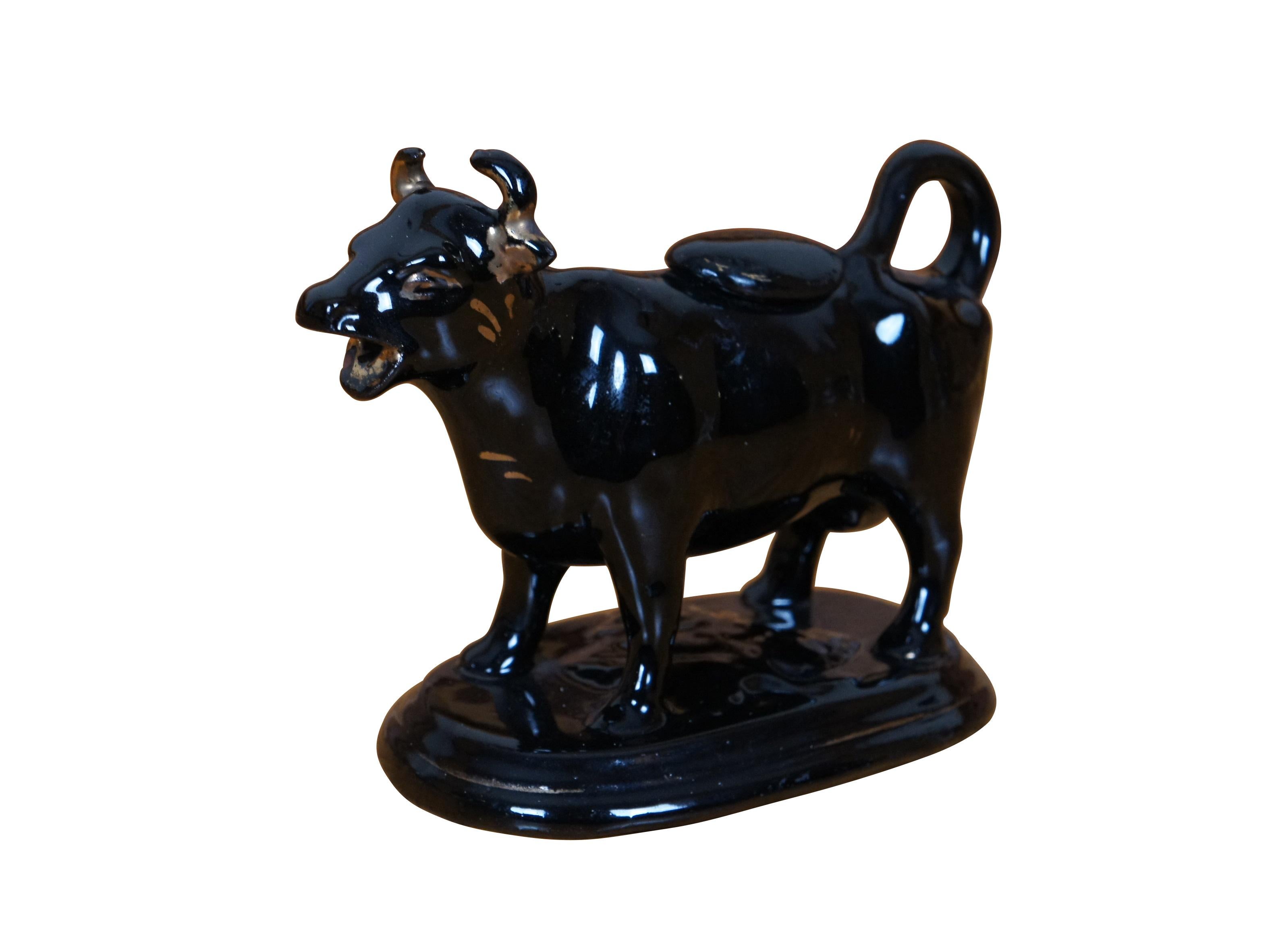 Antica brocca per panna in porcellana di Staffordshire del XIX secolo a forma di mucca con caratteristiche dorate, posta su una base ovale modellata con una margherita. L'intera superficie è rifinita con uno smalto lucido di colore marrone