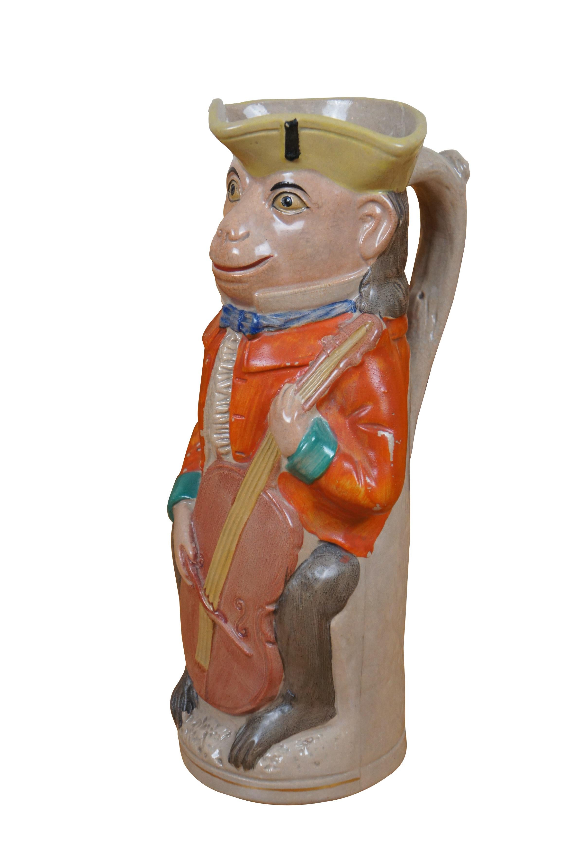 Antique 19th century English Staffordshire ceramic anthropomorphic toby jug / pitcher in the shape of a monkey dressed in British colonial clothing and playing the cello.

Dimensions:
6.5