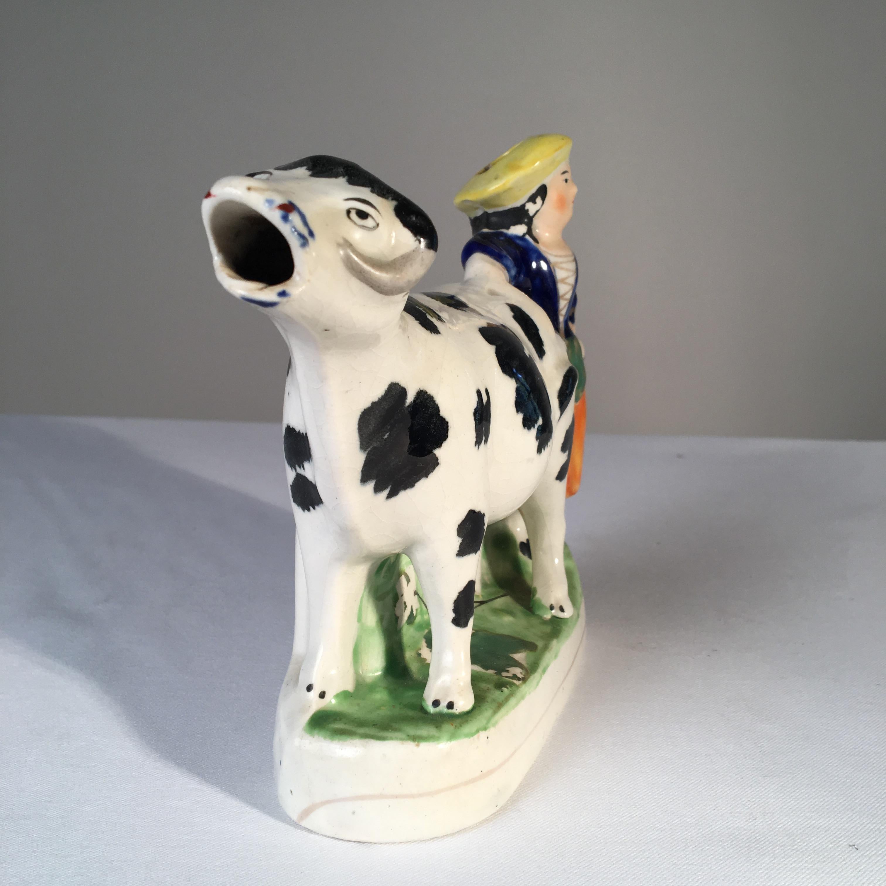 An antique Staffordshire cow creamer with figure of woman, circa 1830.