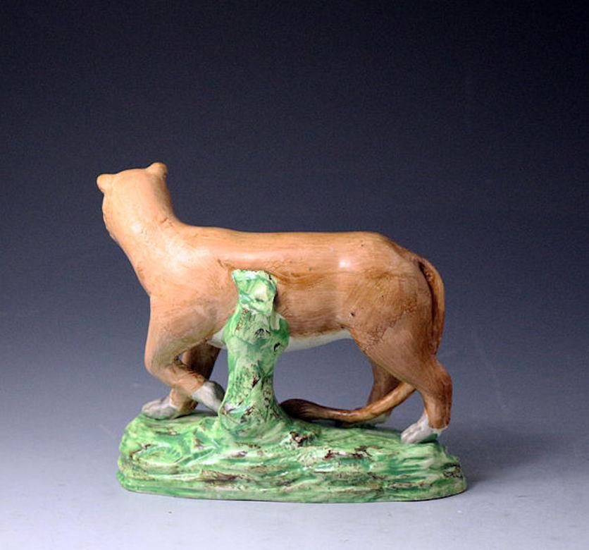 A rare pottery pearlware figure of a lioness standing on a green base. The figure is expressively modelled and decorated. The piece was intended to be made with bocage; this feature is missing and left the pottery with this intention. This original
