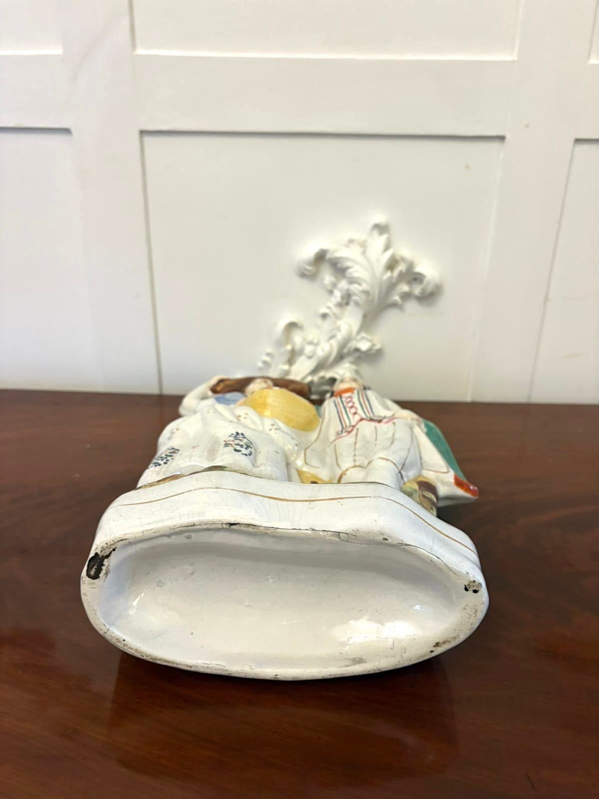 Un incantevole gruppo di figure in ceramica dello Staffordshire raffigurante una coppia di campagna, con la donna che porta un covone di grano sulla testa e tiene in mano un cesto di frutta, il suo compagno in abiti rustici con un mantello verde e