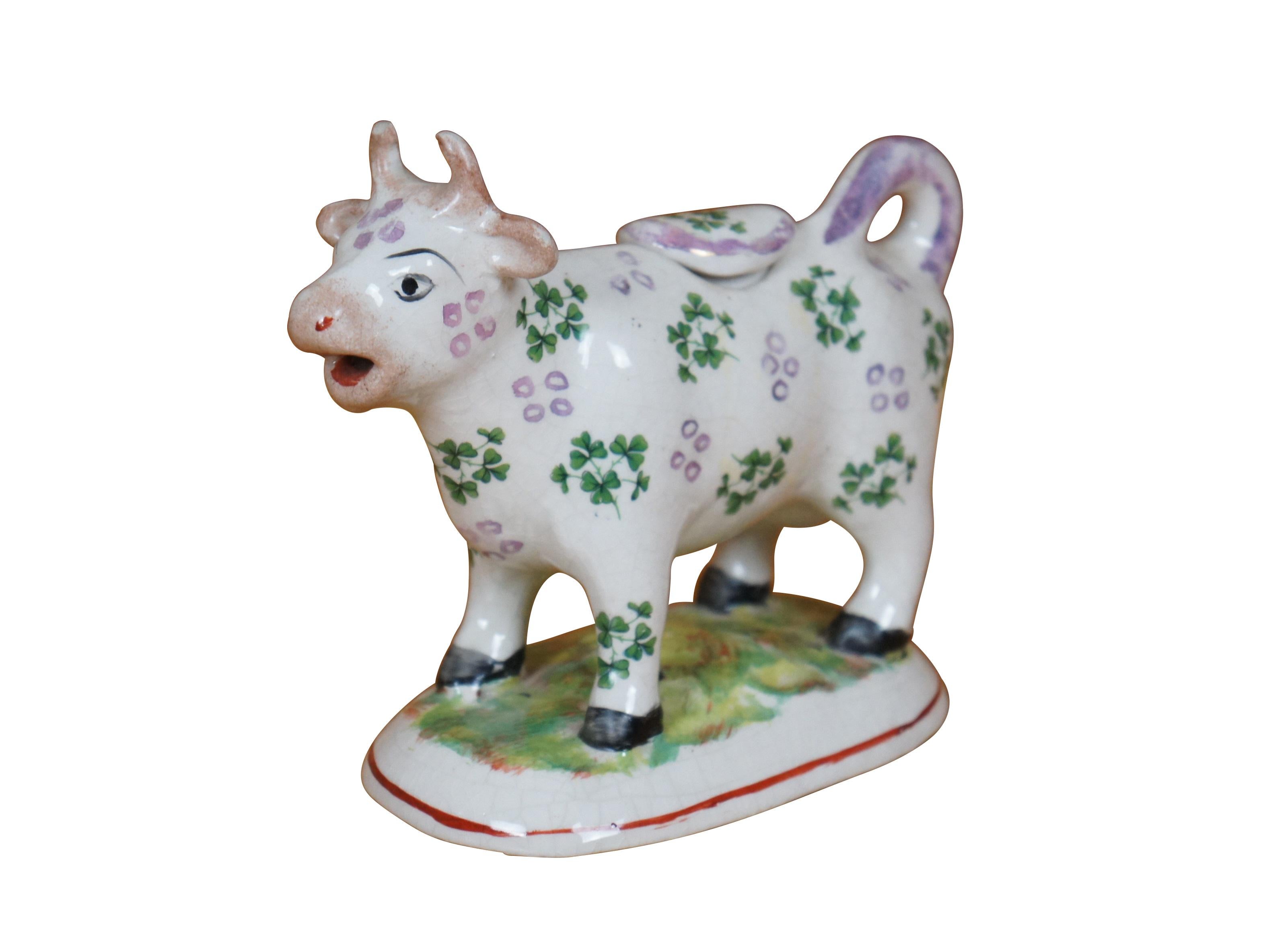 Seltener antiker Staffordshire-Porzellankrug aus dem 19. Jahrhundert in Form einer weißen Kuh mit irisierenden lavendelfarbenen/hellvioletten Flecken, bemalt mit Kleeblättern, auf einem ovalen Sockel mit Gras. Der Schwanz rollt sich zu einem Griff