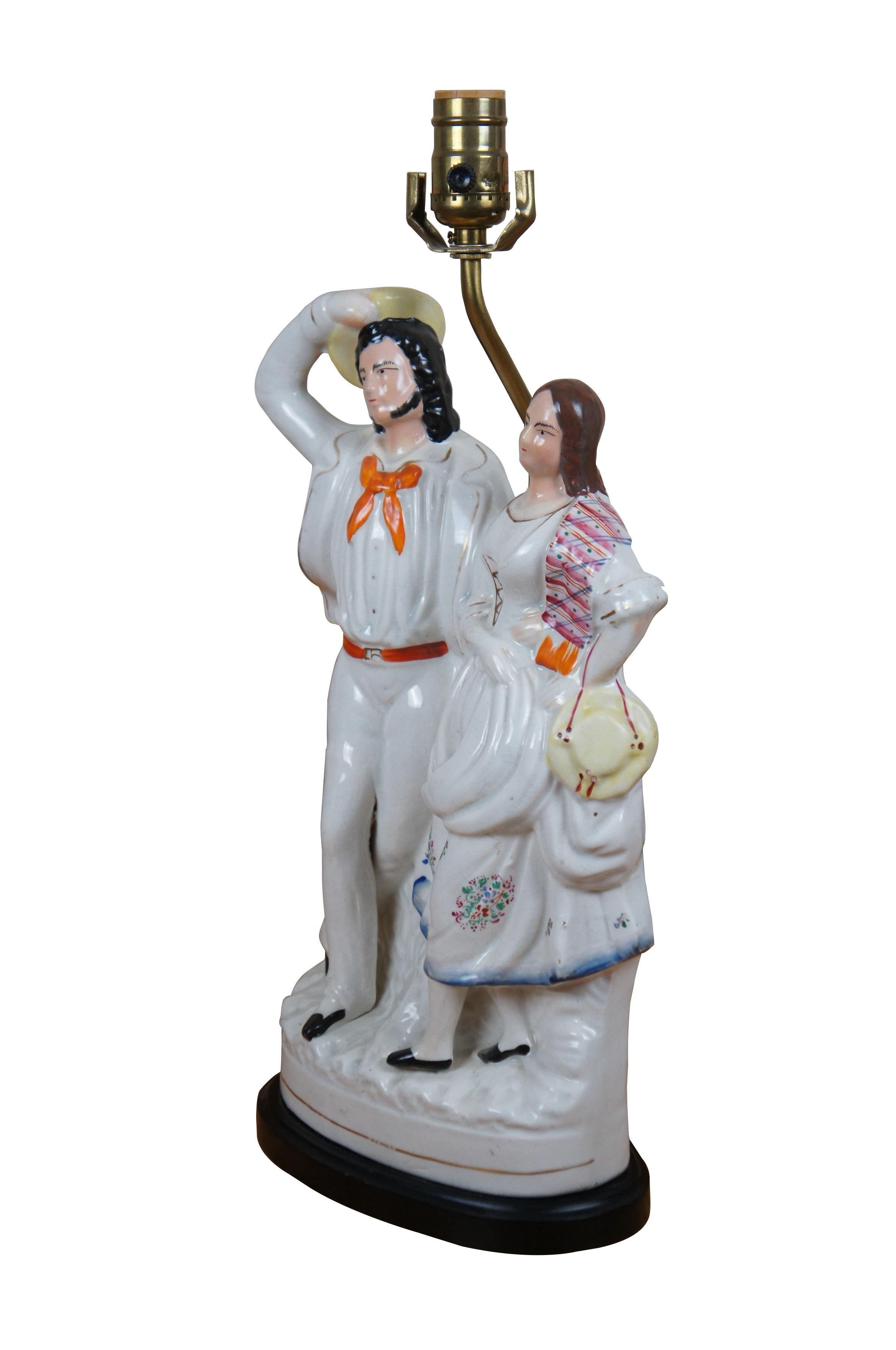 Ancienne figurine à dos plat en porcelaine anglaise du Staffordshire du XIXe siècle transformée en lampe de table, représentant un homme habillé en marin et une femme avec un chapeau jaune et un châle rayé. Base en bois noir ; comprend une harpe et
